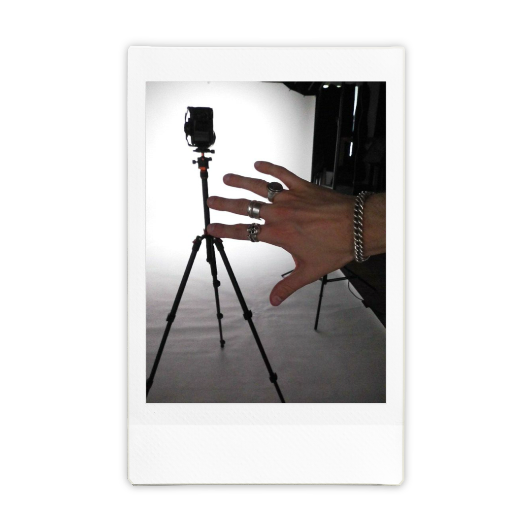 Hand with rings and bracelet in front of a camera on tripod in a photography studio