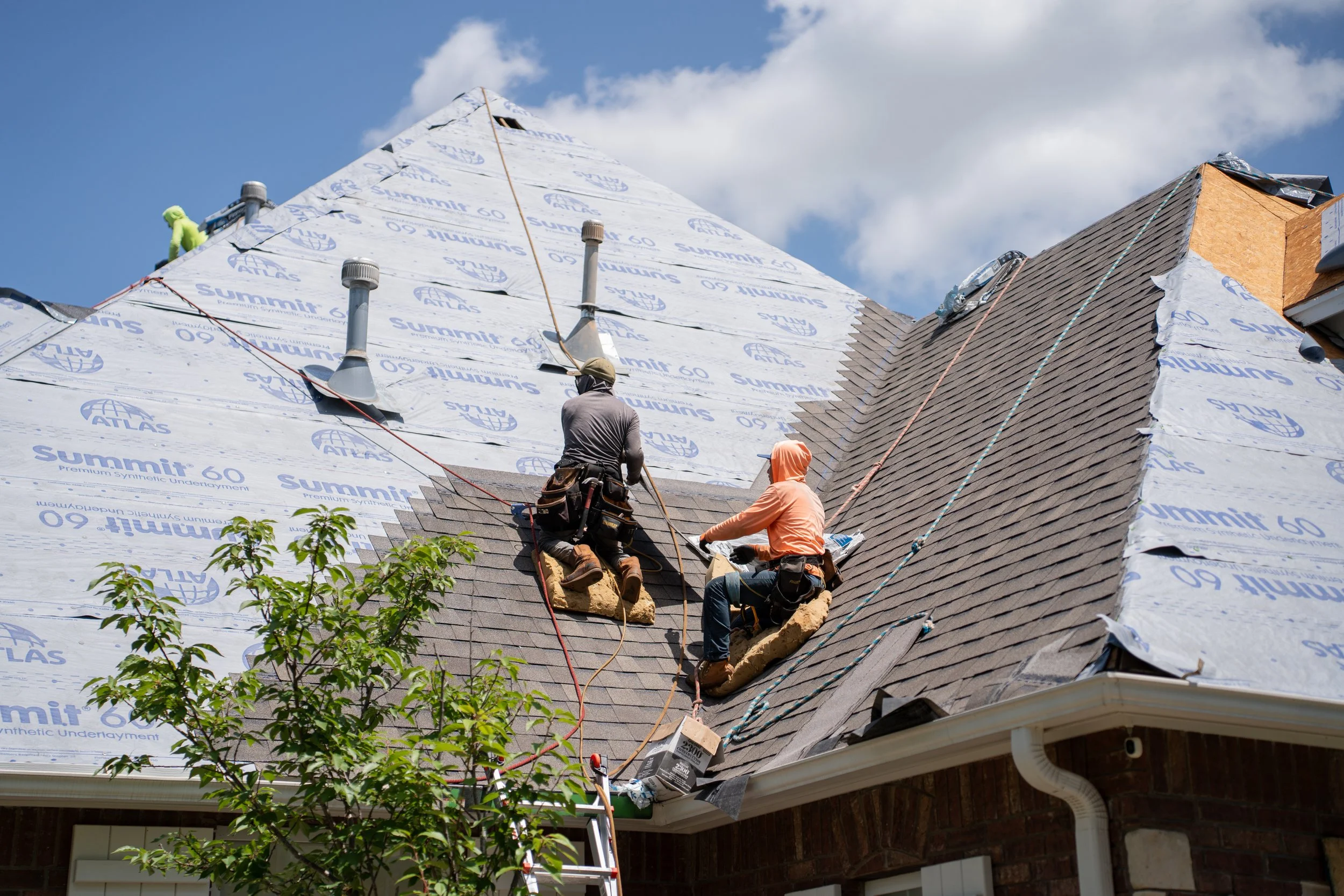 Two people working on replacing a roof with new shingles