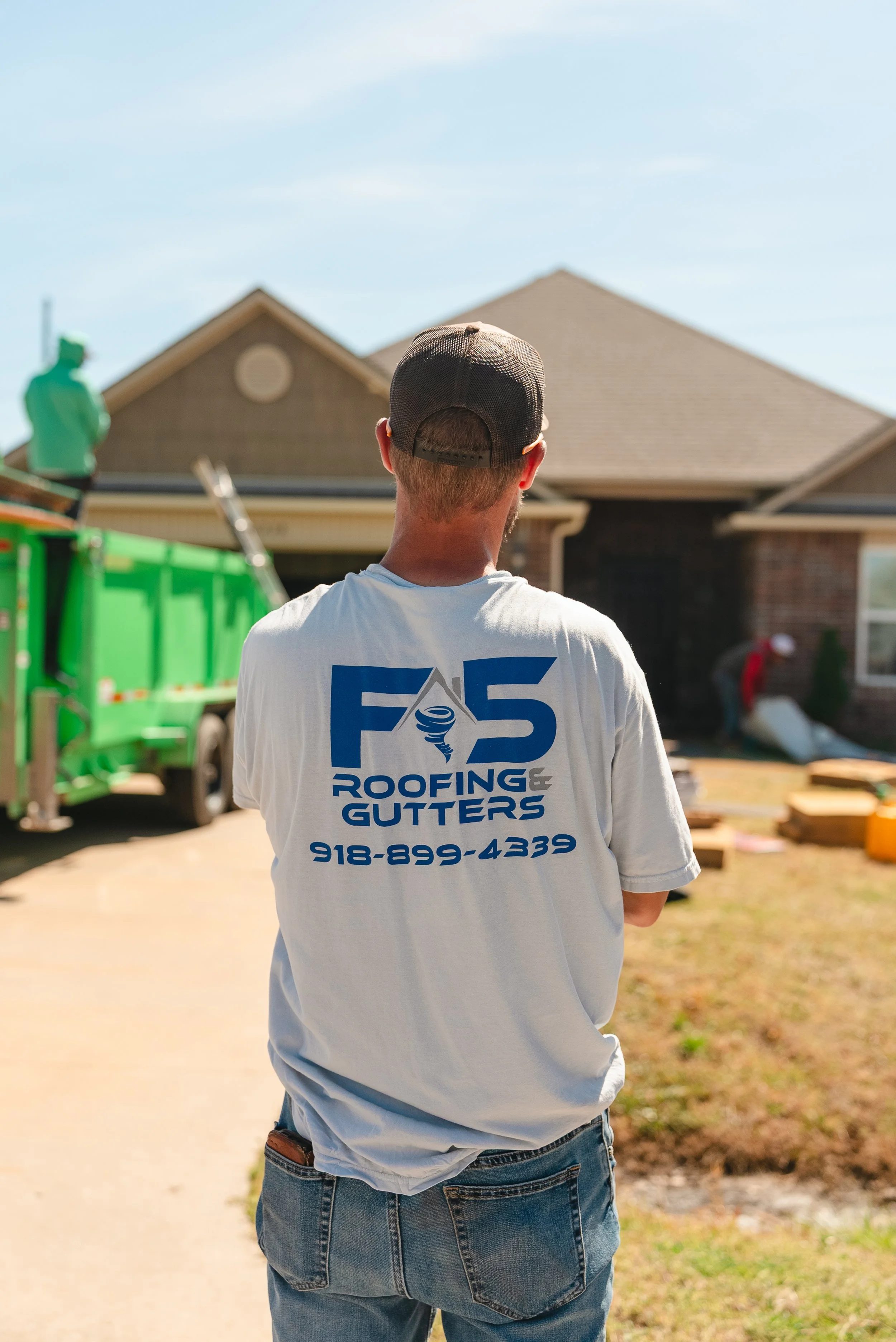 A man overseeing a roof and gutter replacement job with F5's logo and a phone number that reads "918-899-4339" in Oklahoma