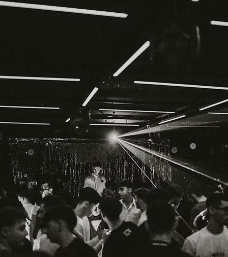 Una scena di una festa o di un club con molte persone e luci al neon sopra