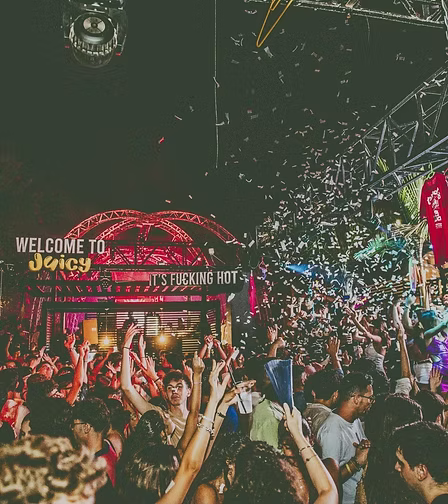 Più persone che ballano e si divertono al concerto Juventus, con luci colorate, drappi e un grande schermo sul palco.