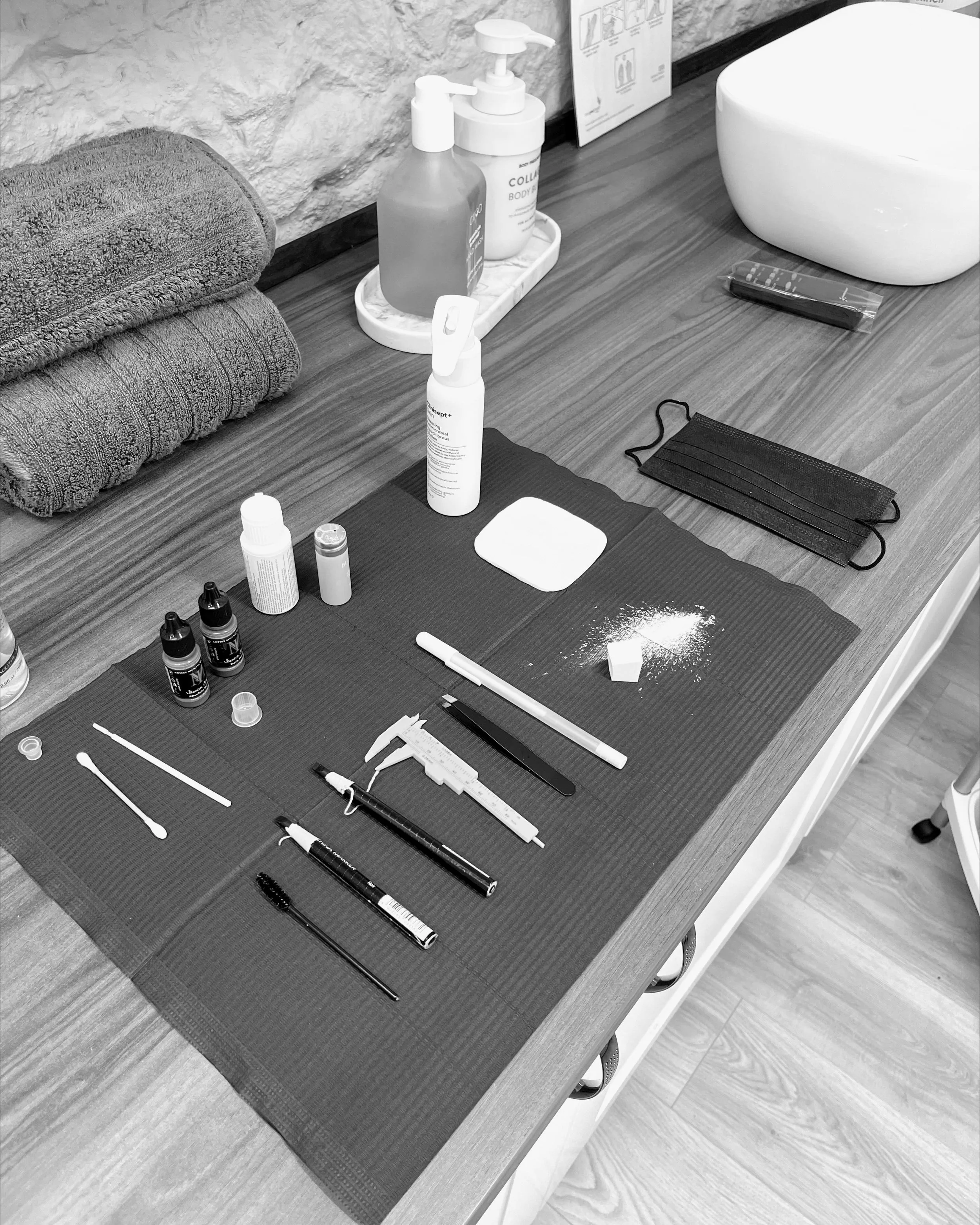 A neatly organised workstation showing permanent makeup tools, disposable supplies and pigments set up on a clean surface before a treatment