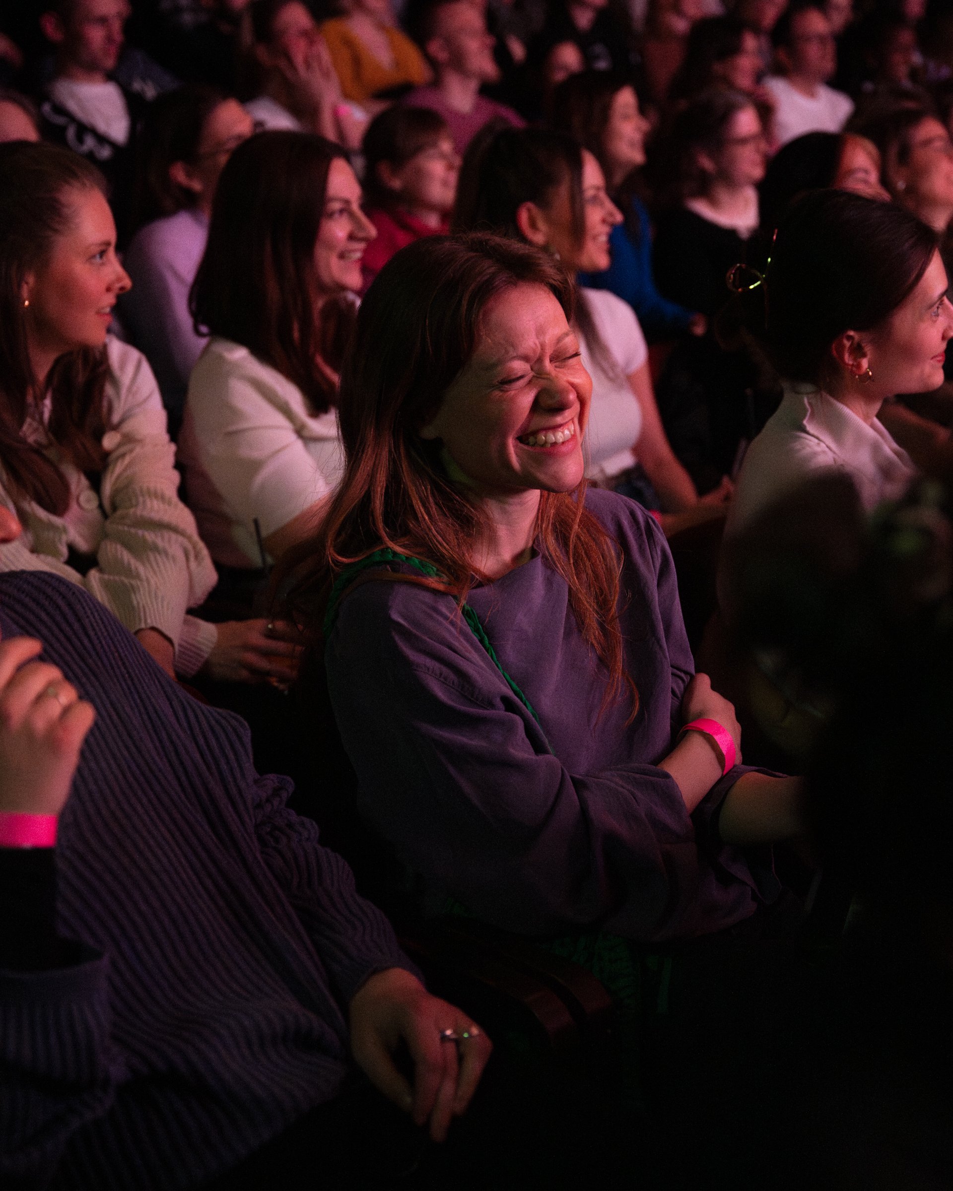 A group of women sitting in an audience, laughing and enjoying a comedy show.