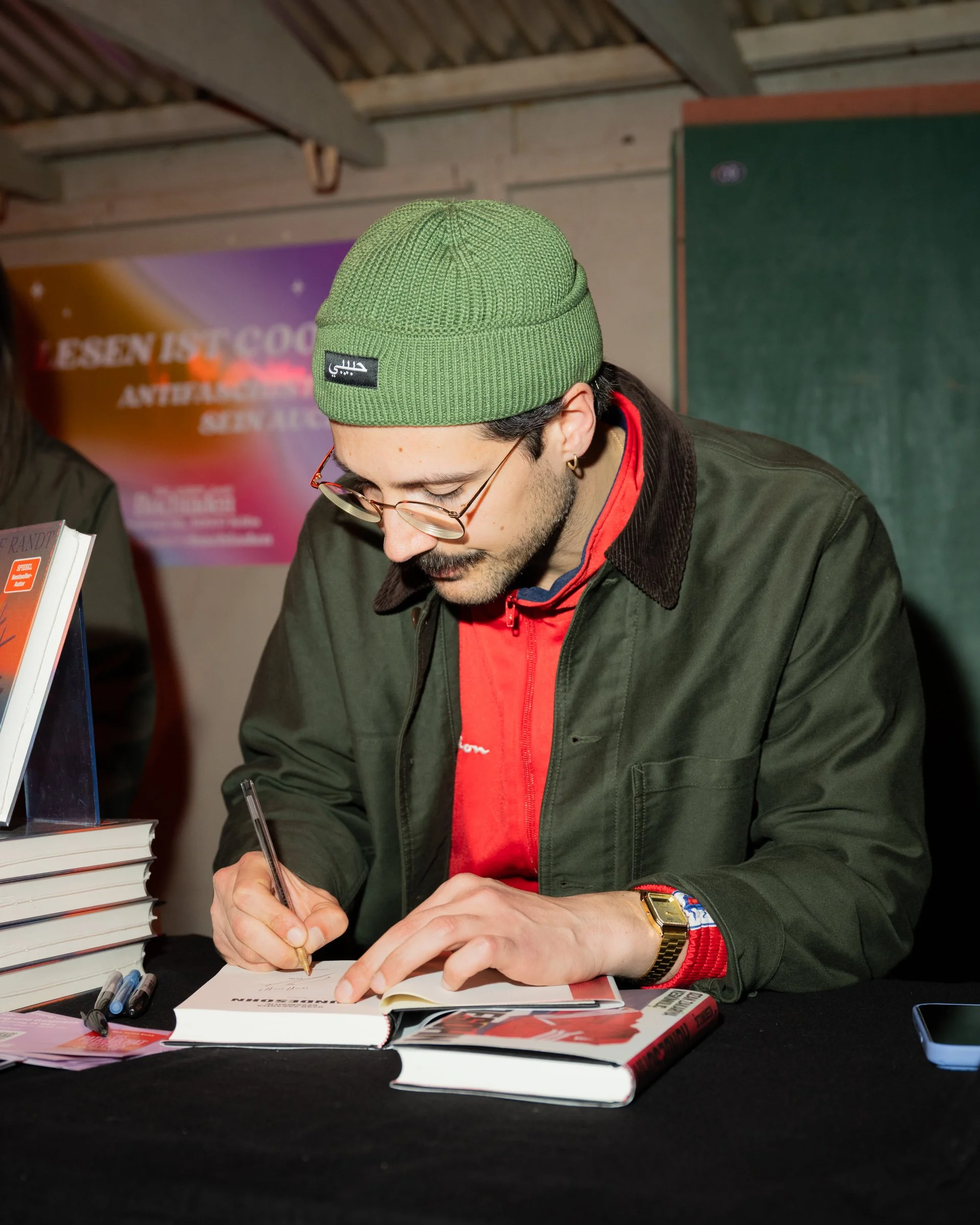 Eventfotografie auf der lit.pop.cologne 2026: Autor Ozan Zakariya Keskinkılıç signiert sein Buch „Hundesohn“ bei einer Lesung