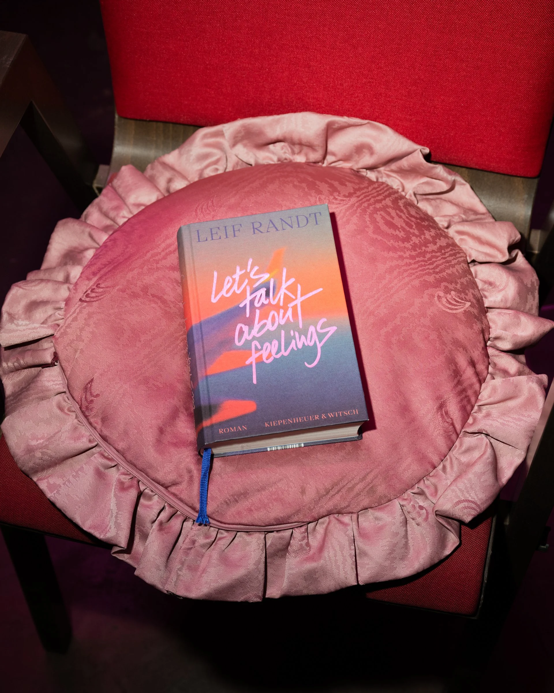 Buchfotografie: „Let’s Talk About Feelings“ von Leif Randt auf einem rosa Samtkissen auf einem Stuhl arrangiert