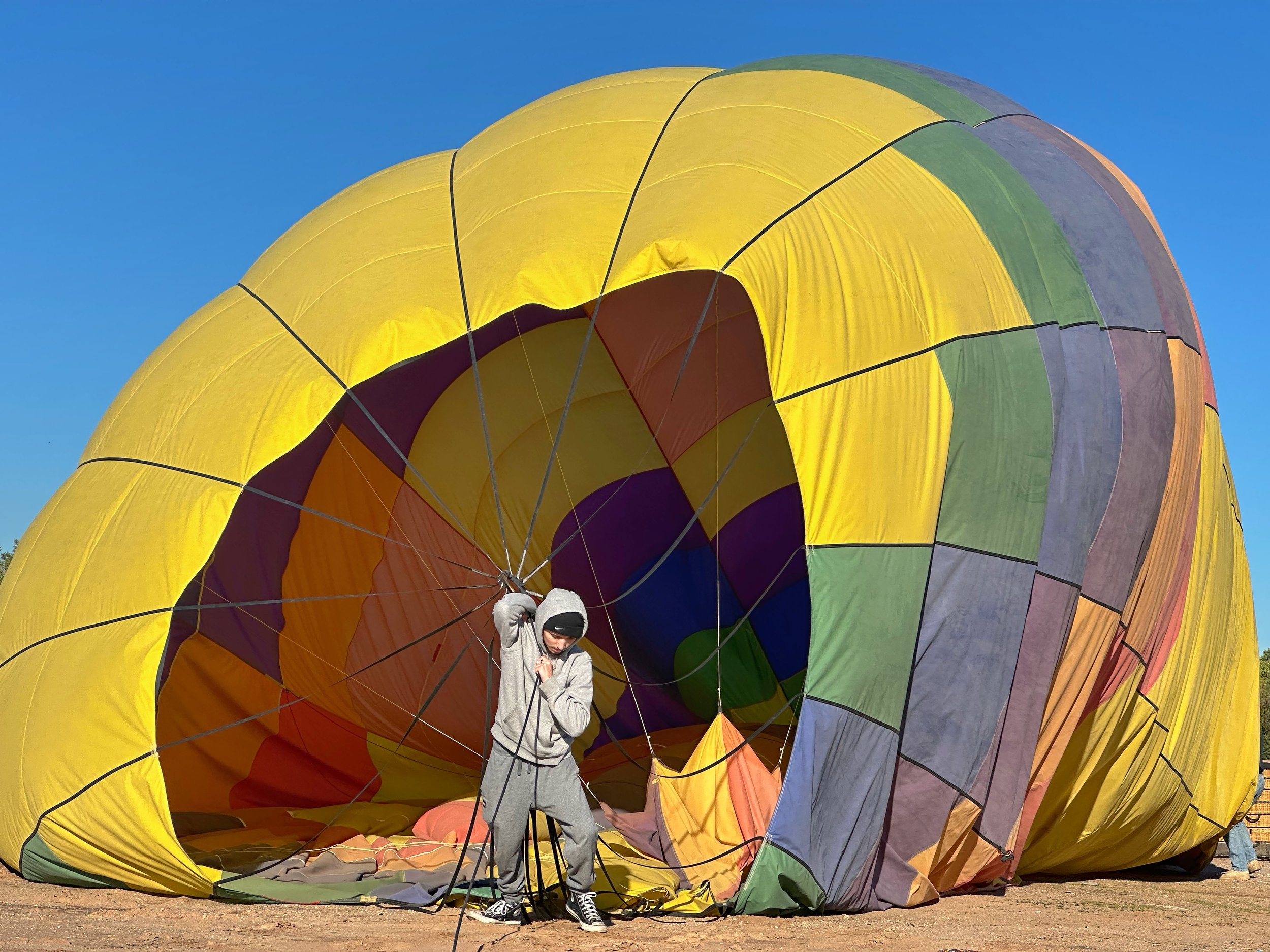 DANCE OF THE GROUND CREW - Albuquerque, New Mexico (October 3, 2026) - This hot air balloon -- one of hundreds launched at the annual Albuquerque Balloon Fiesta -- landed on an empty dirt lot in the middle of the city. The ground crew has to hold on 