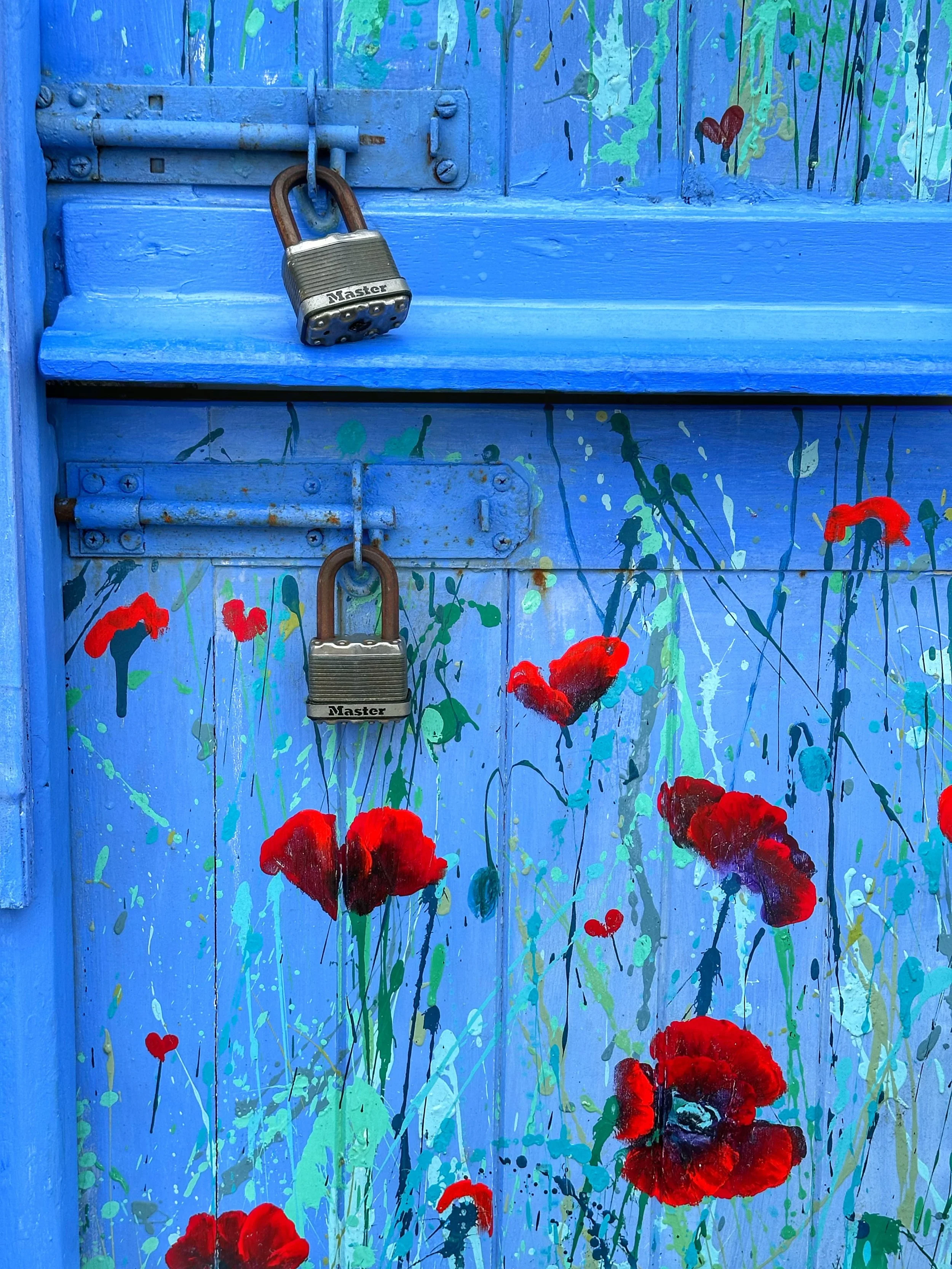 DOUBLE-LOCKED - Brighton, England (July 5, 2024) - This is a detail of the double-locked and dead-bolted door of the Tina Davies Art Gallery, with permission of the door artist. The juxtaposition and contrast of the hard steel padlocks with the free-