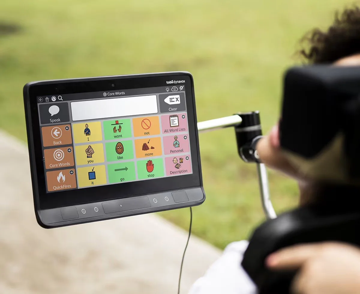 A person in a wheelchair uses a communication device outdoors.