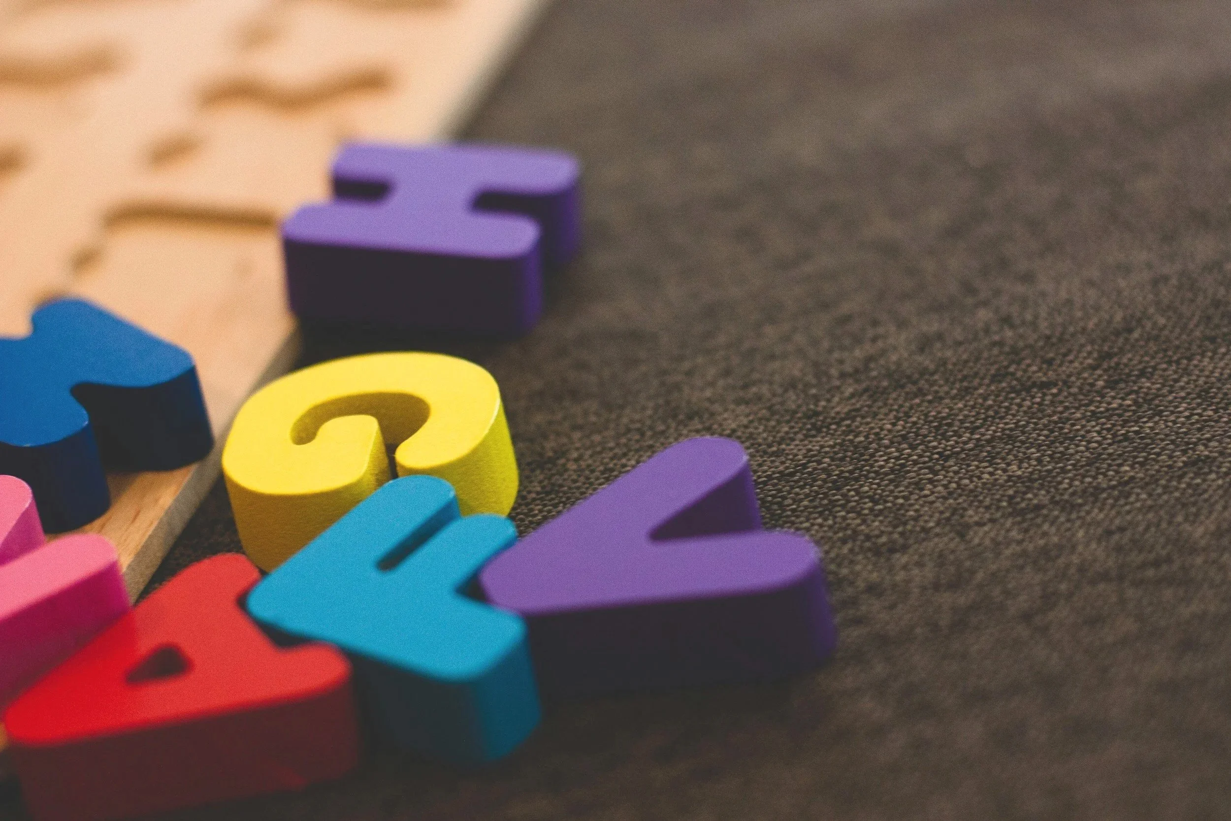 Close-up of colorful foam numbers and letters arranged on a dark textile surface.