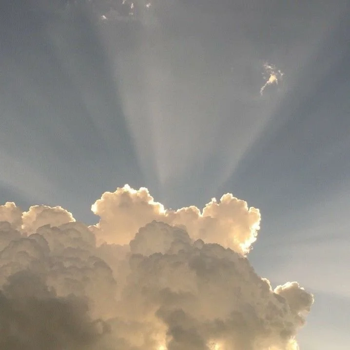 Sky with large, fluffy clouds and sun rays breaking through.