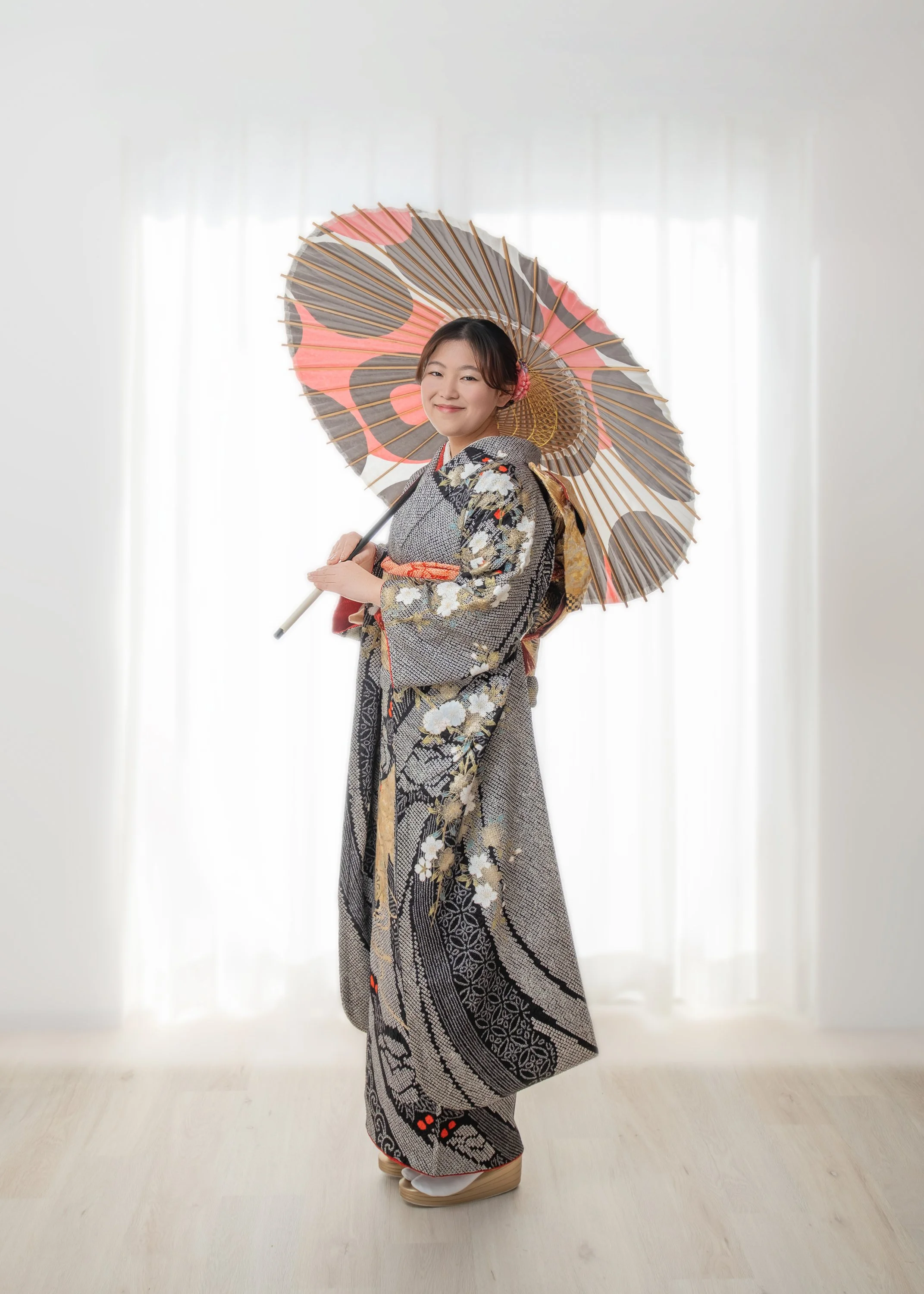 着物を着た女性が和傘を持って微笑んでいる写真