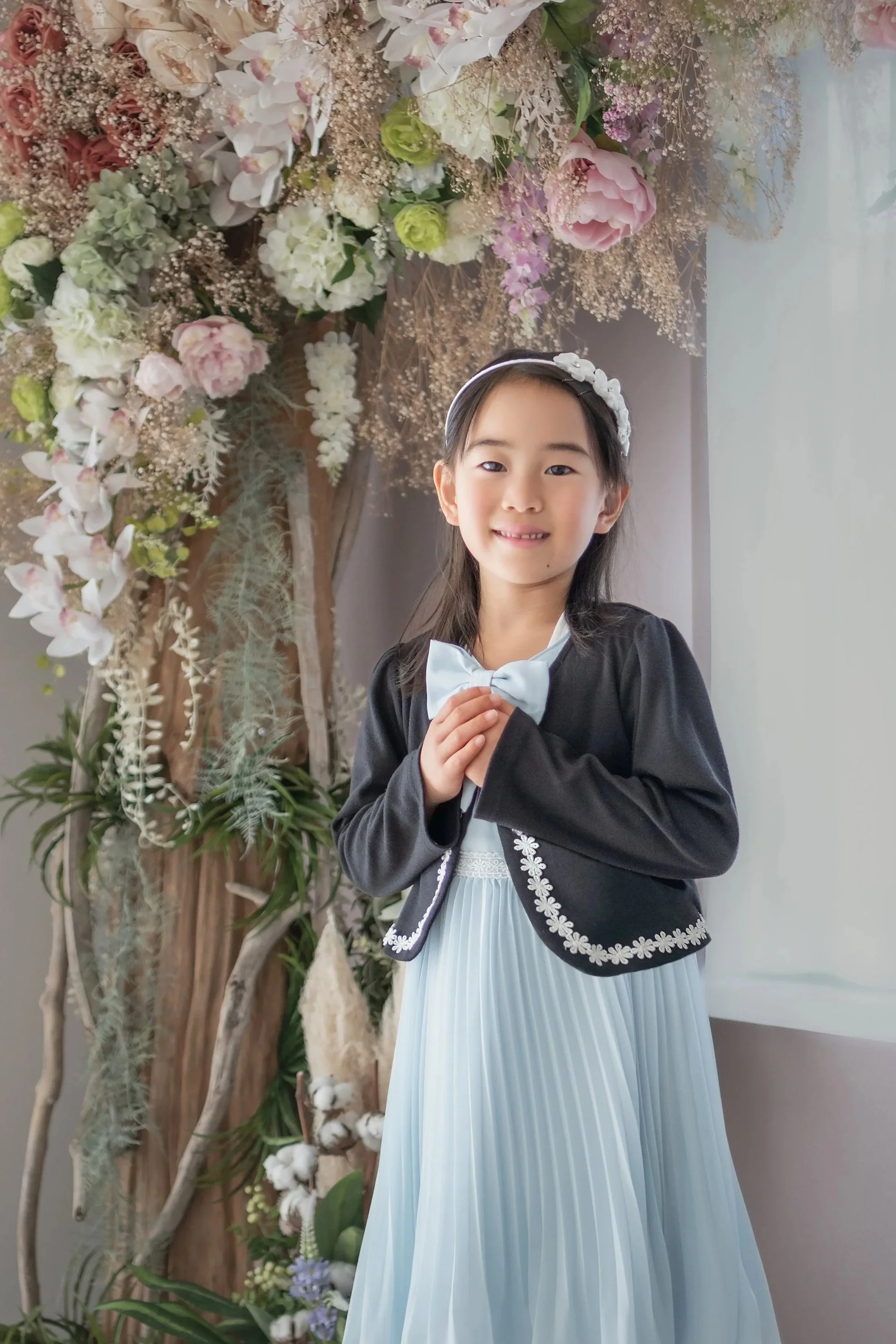 花の飾りのある背景の前で微笑む少女