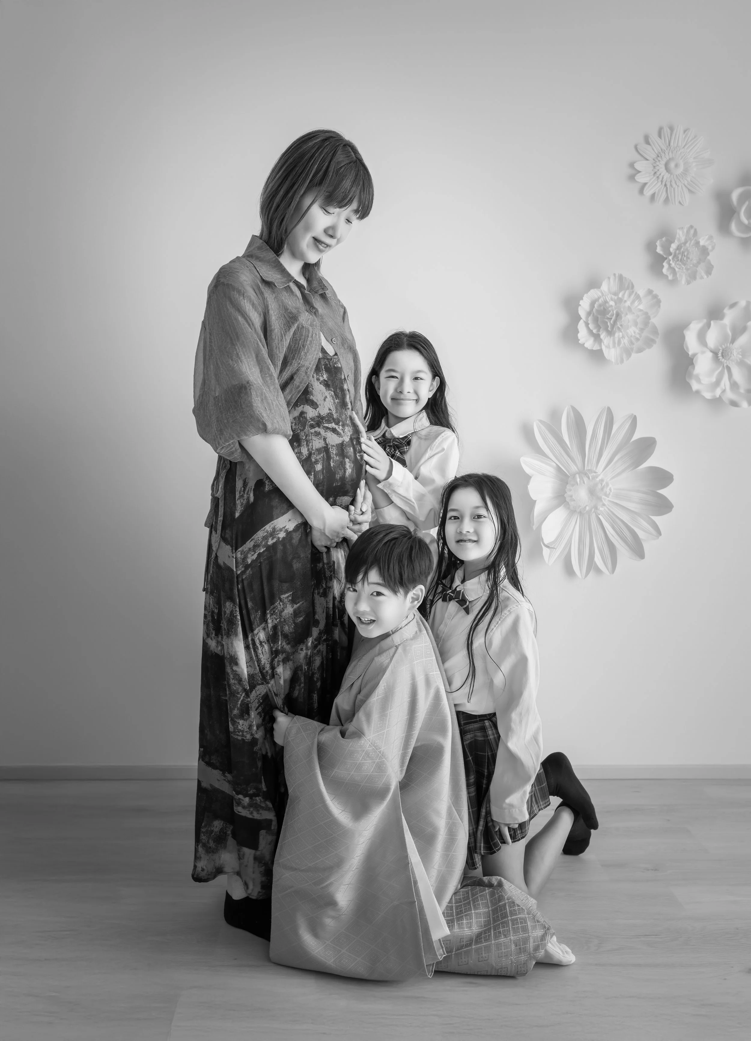 妊婦と三人の子供がポーズを取るモノクロ写真