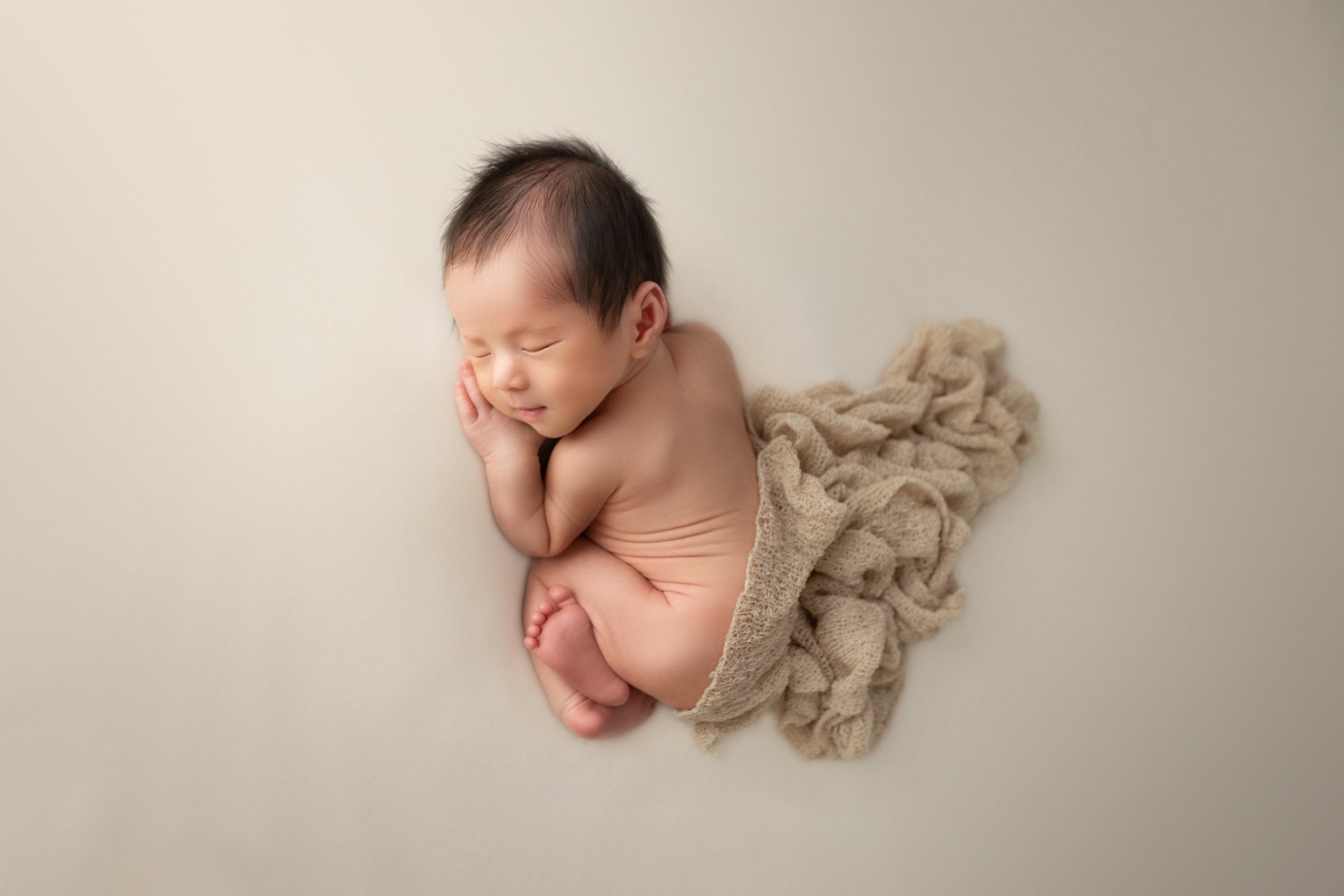 眠っている赤ちゃんの写真。赤ちゃんは横向きで手を頬にあてている。