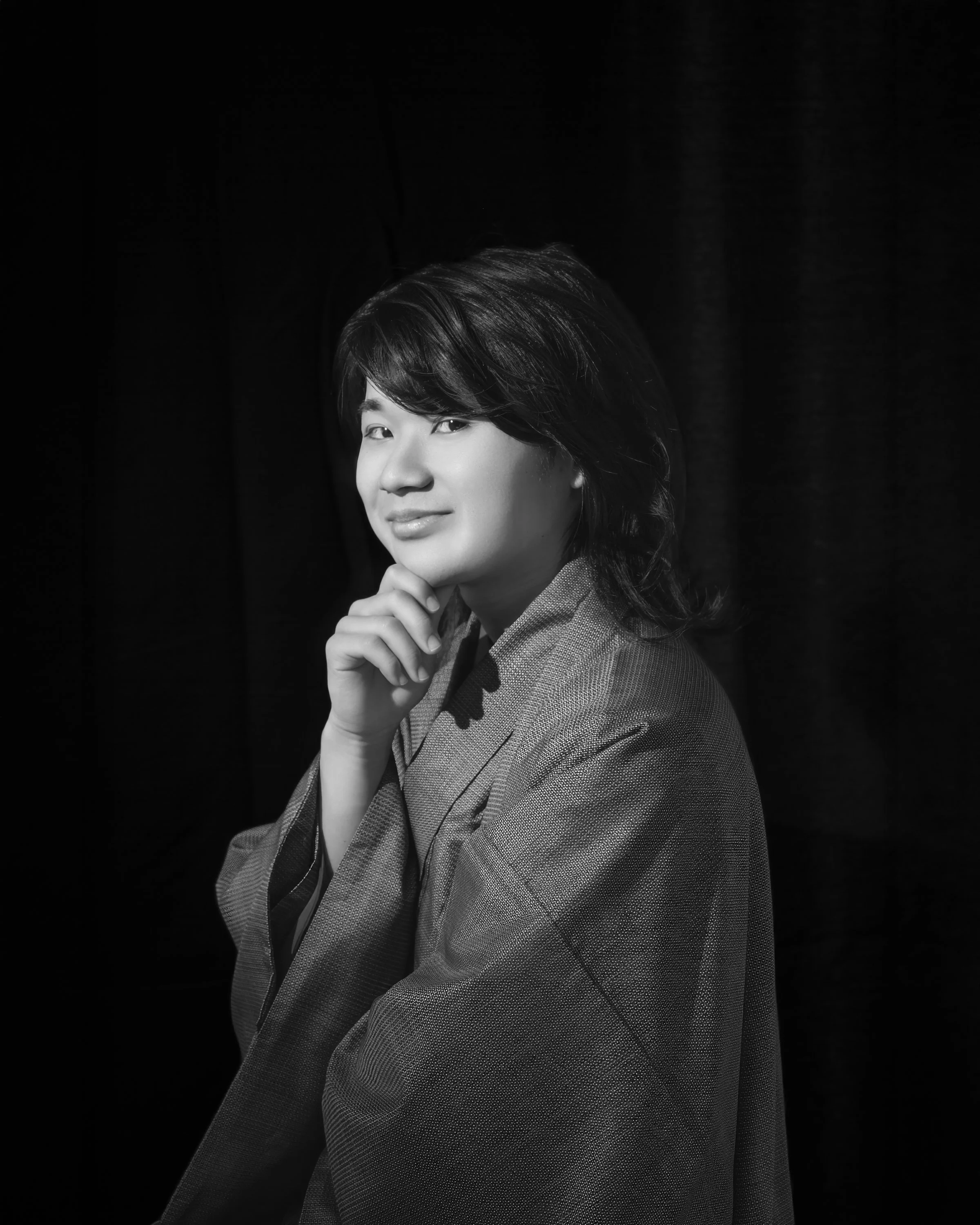 黒い背景の前でポーズをとる若い男性の肖像写真。