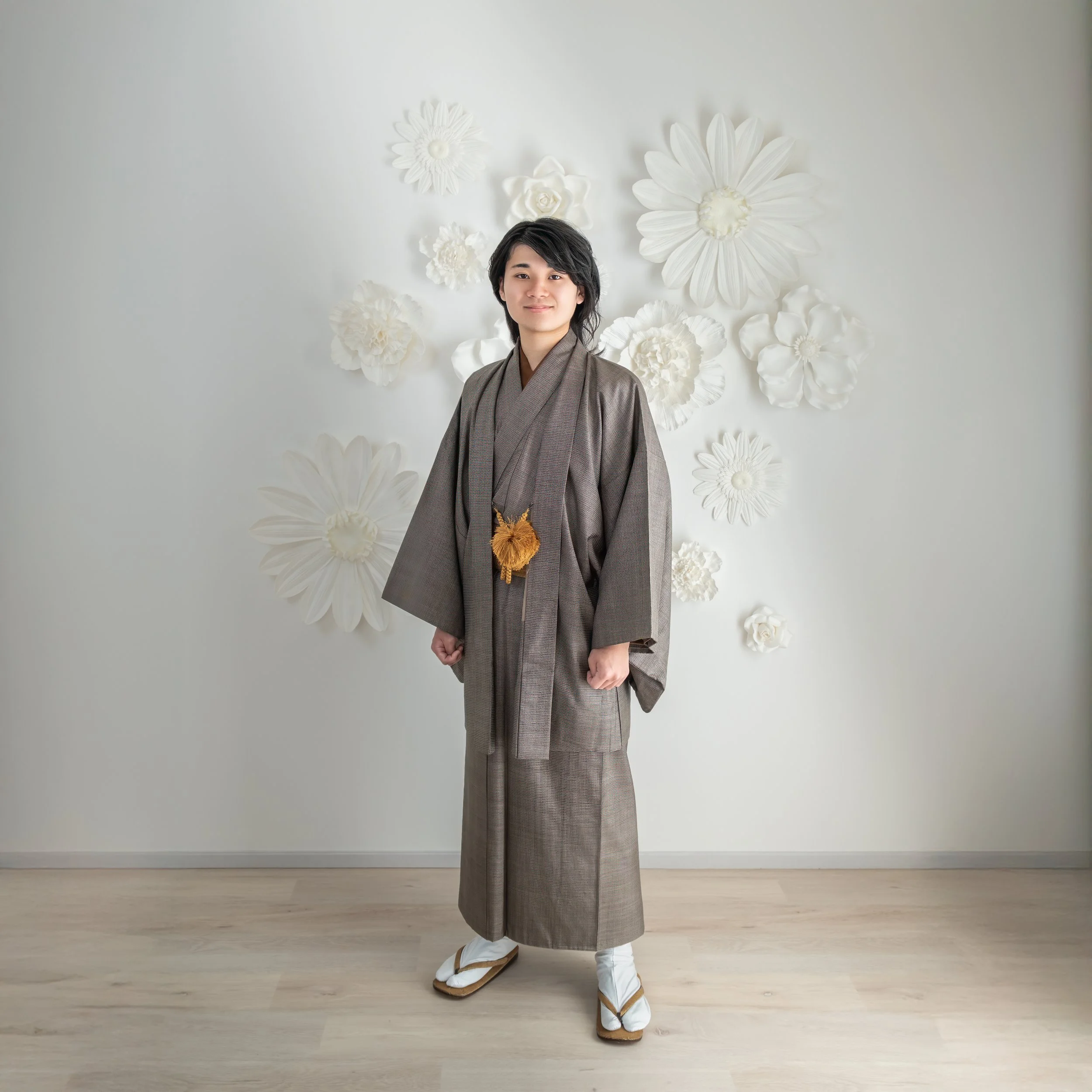 着物を着た男性が和風の背景の前に立っている