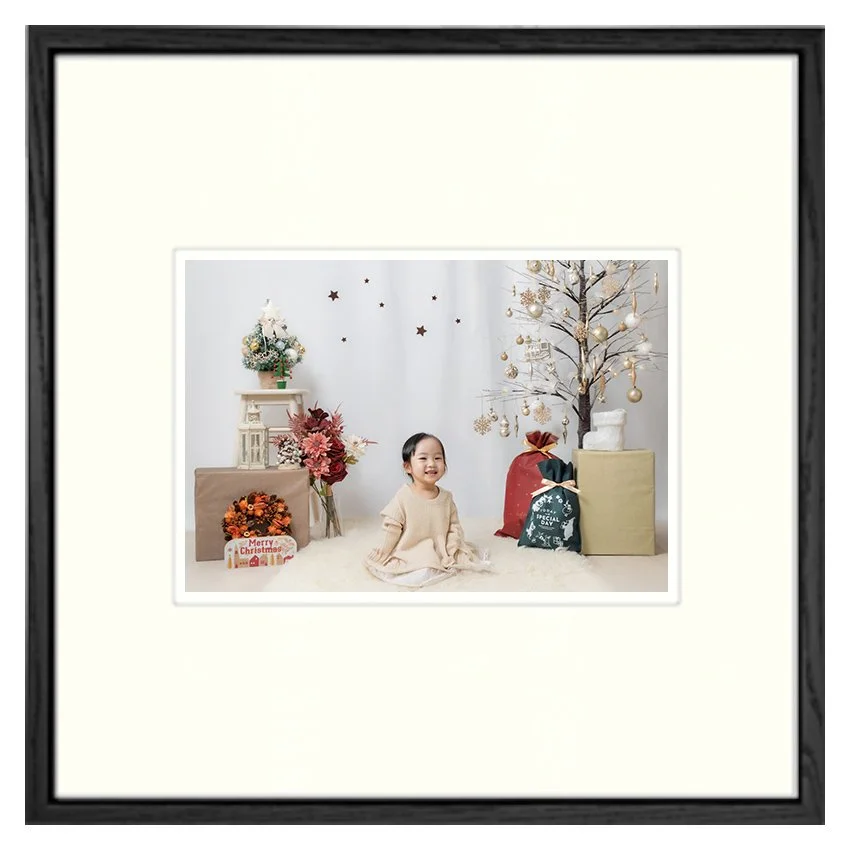 クリスマスの飾り付けのある部屋で子供が笑顔で座っている写真