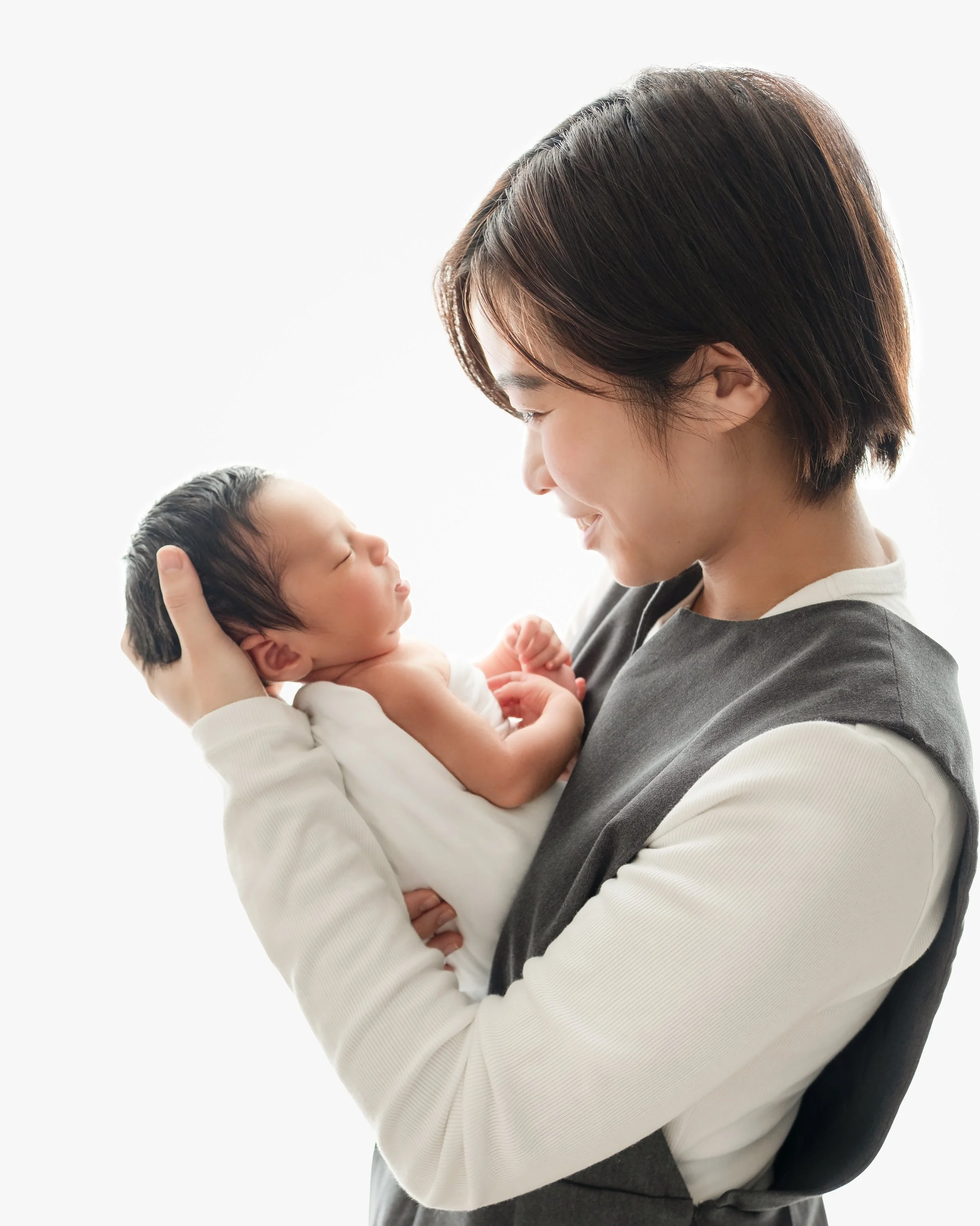 母親が抱く赤ちゃんの写真。母親は笑顔で赤ちゃんを見つめている。