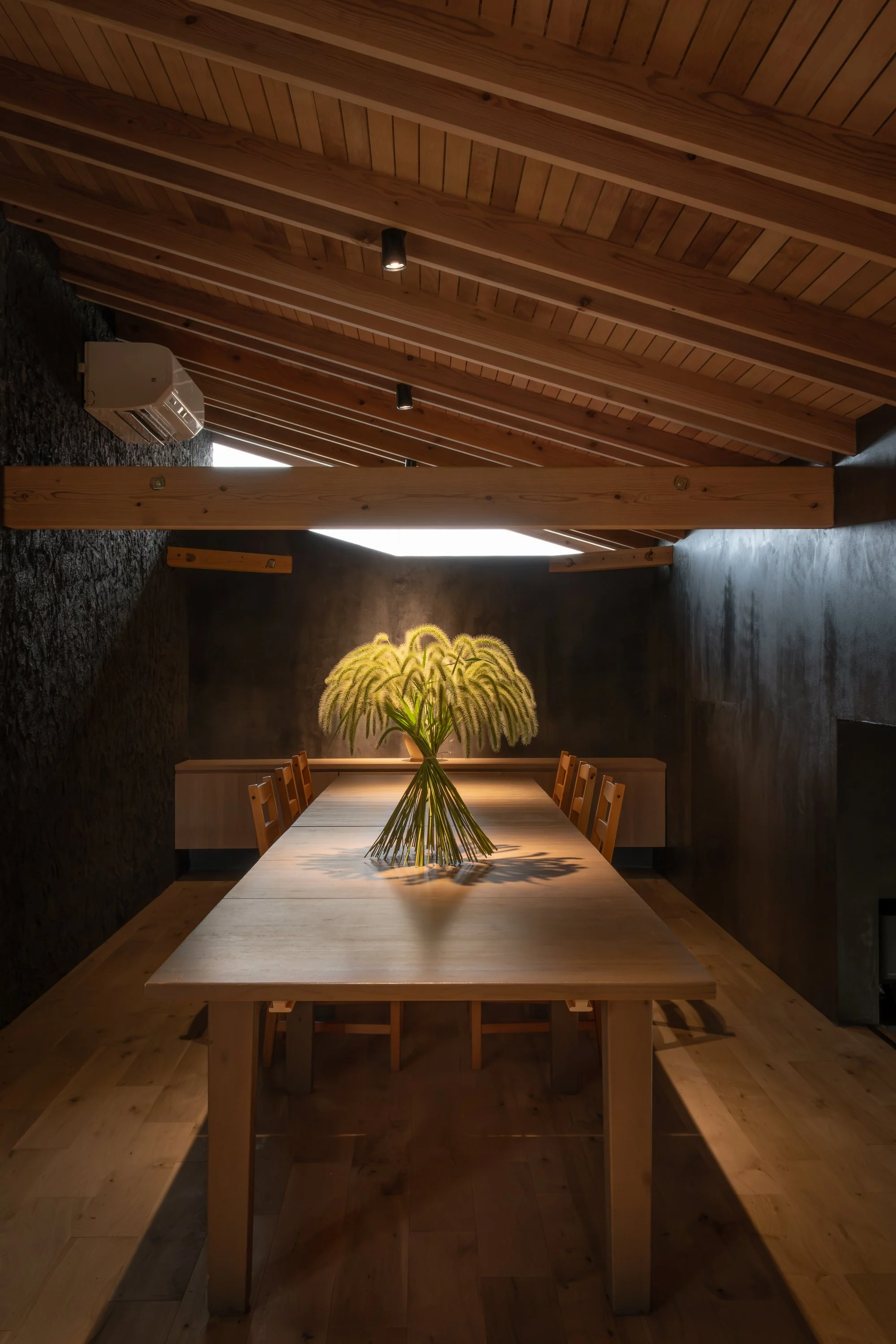 木製のテーブルの上に黄色い花のブーケが置かれたシンプルなダイニングルーム