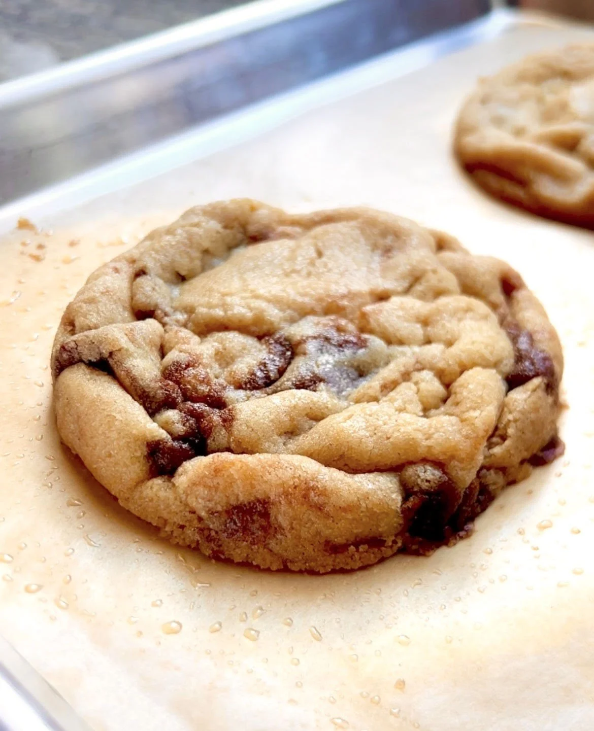 Cinnamon Roll Cookies_1 cookie close up on baking sheet and tan parchment paper.jpg