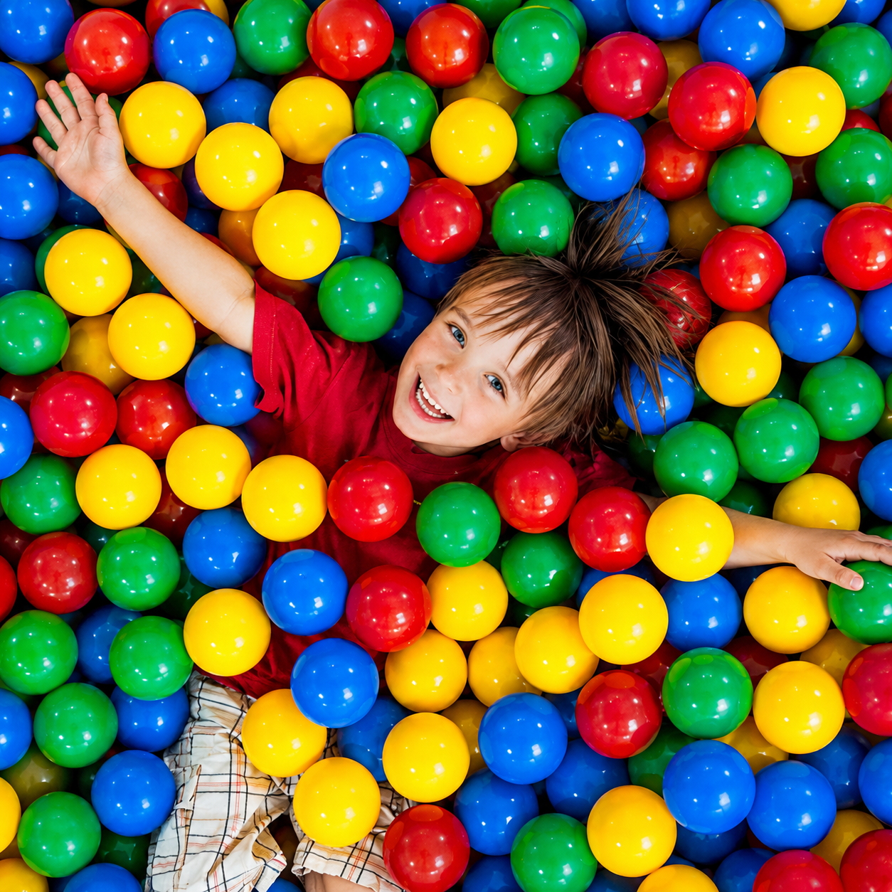 Happy child enjoying play-based learning activities in a colorful ball pit at Little Hugz, promoting creativity, confidence, and early childhood development.