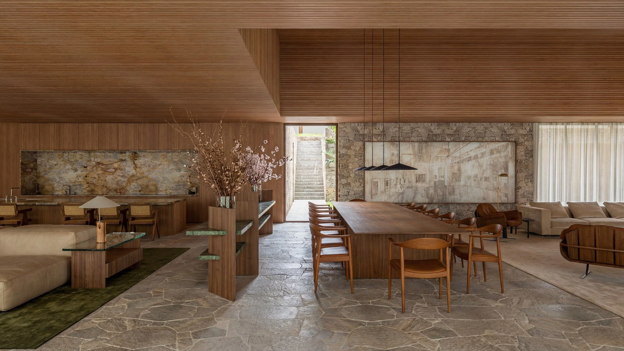 Na Casa Silente, os espa&ccedil;os sociais se organizam com naturalidade, em uma fluidez cont&iacute;nua entre arquitetura, interiores e paisagem. Pedra, madeira e tecidos comp&otilde;em uma materialidade essencial, que acolhe.

A luz conduz a experi