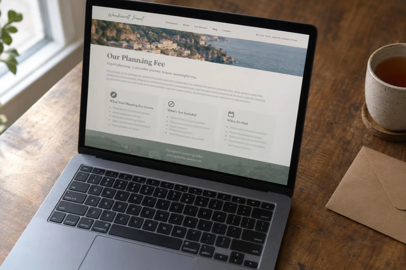 Laptop displaying an example travel planning fee webpage on a wooden table beside a cup of tea and envelope