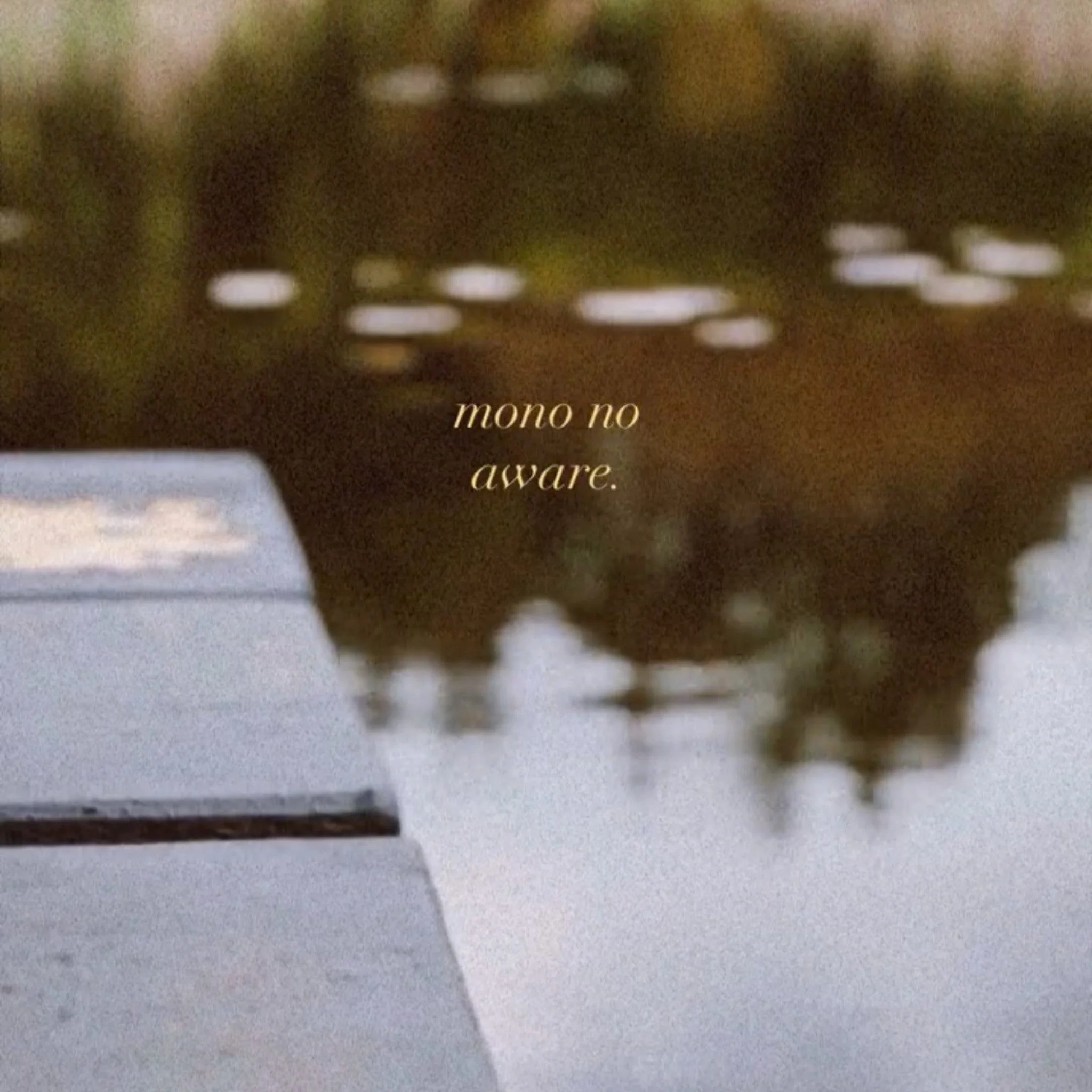 Close-up of a piano keyboard with the text 'mono no aware.' overlaid, and a blurred background of a lake and trees.