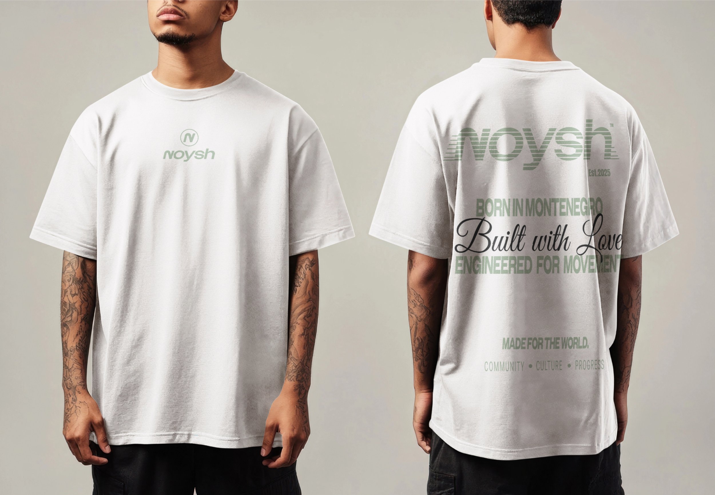 White T-shirt with green text on front and back, worn by a young man with tattoos on arms, studio background.