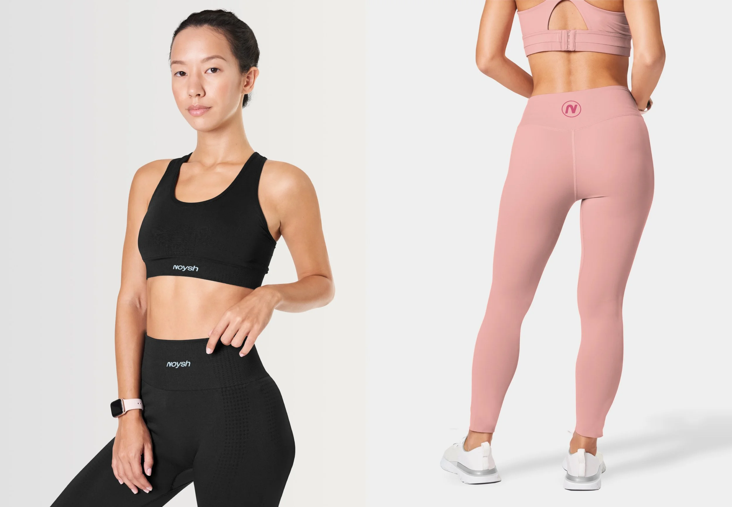 A woman in black sportswear, including a sports bra and leggings, standing with her left hand on her hip and wearing a smartwatch, alongside a woman from the back in pink leggings and a matching sports bra, standing with her hands behind her back.