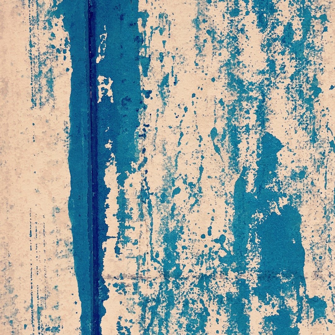 Abstract textured wall with blue paint splatters and peeling paint.