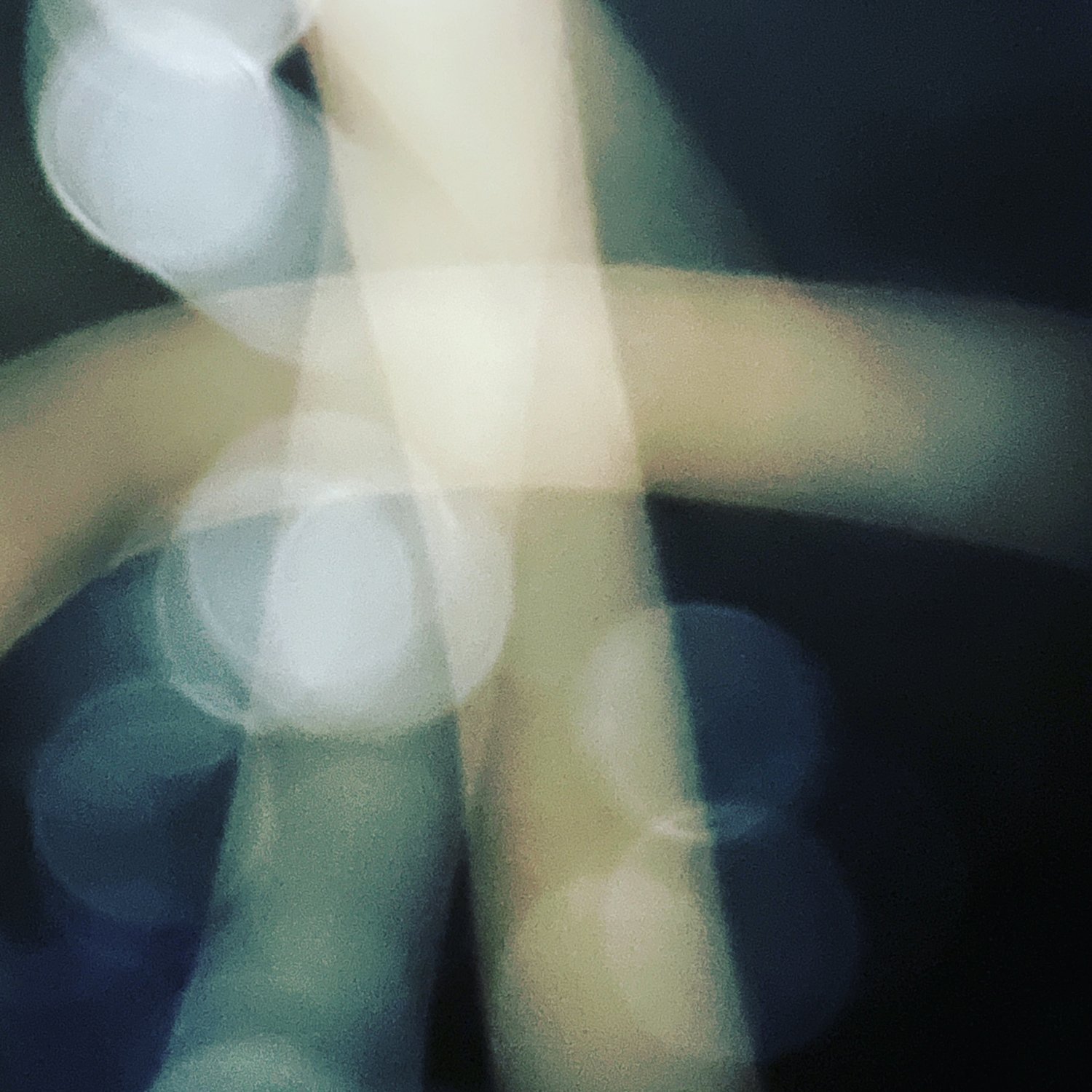 Abstract image with blurred circles of light in shades of white, yellow, blue, and black.
