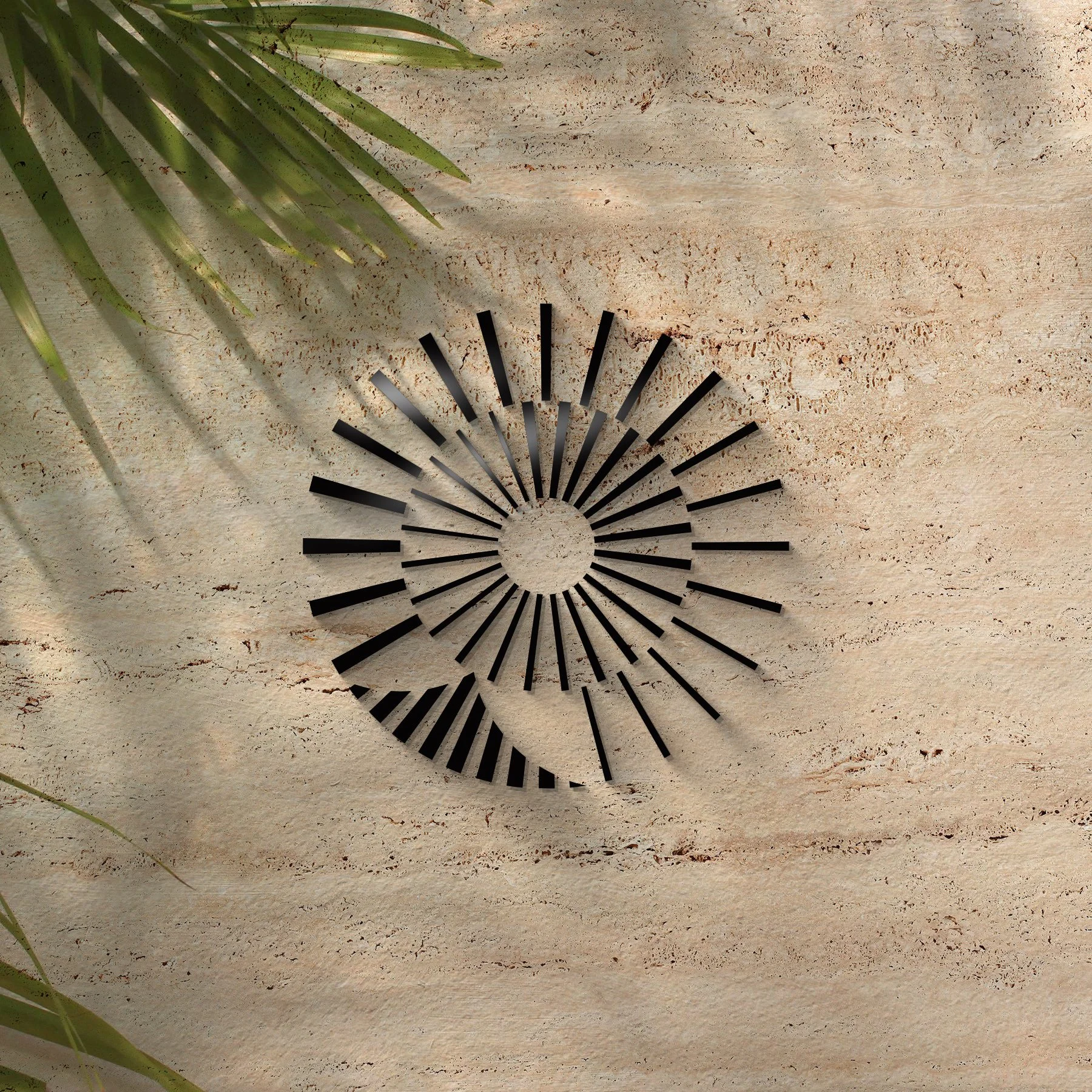 A black metal wall clock with a modern sunburst design, placed on a beige textured surface with a green plant in the upper left corner.