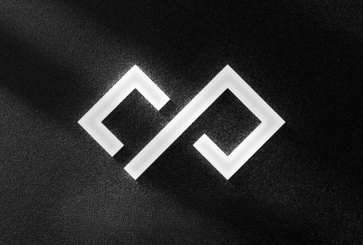 A black textured surface with a luminous geometric design consisting of two overlapping squares with open sides, creating an abstract pattern.