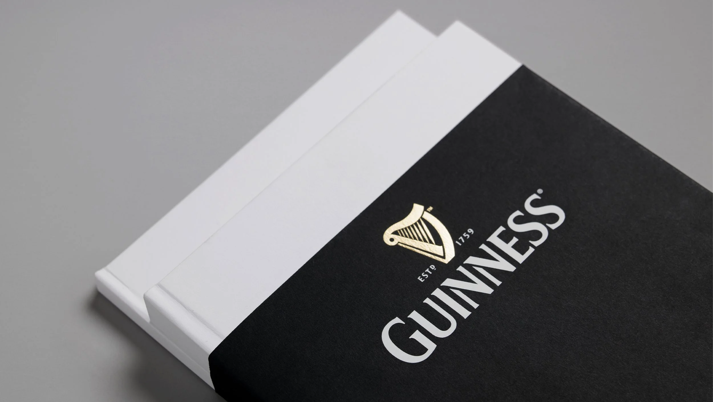 Close-up of a Guinness beer coaster and lid, with the Guinness logo and harp symbol visible on a black background.