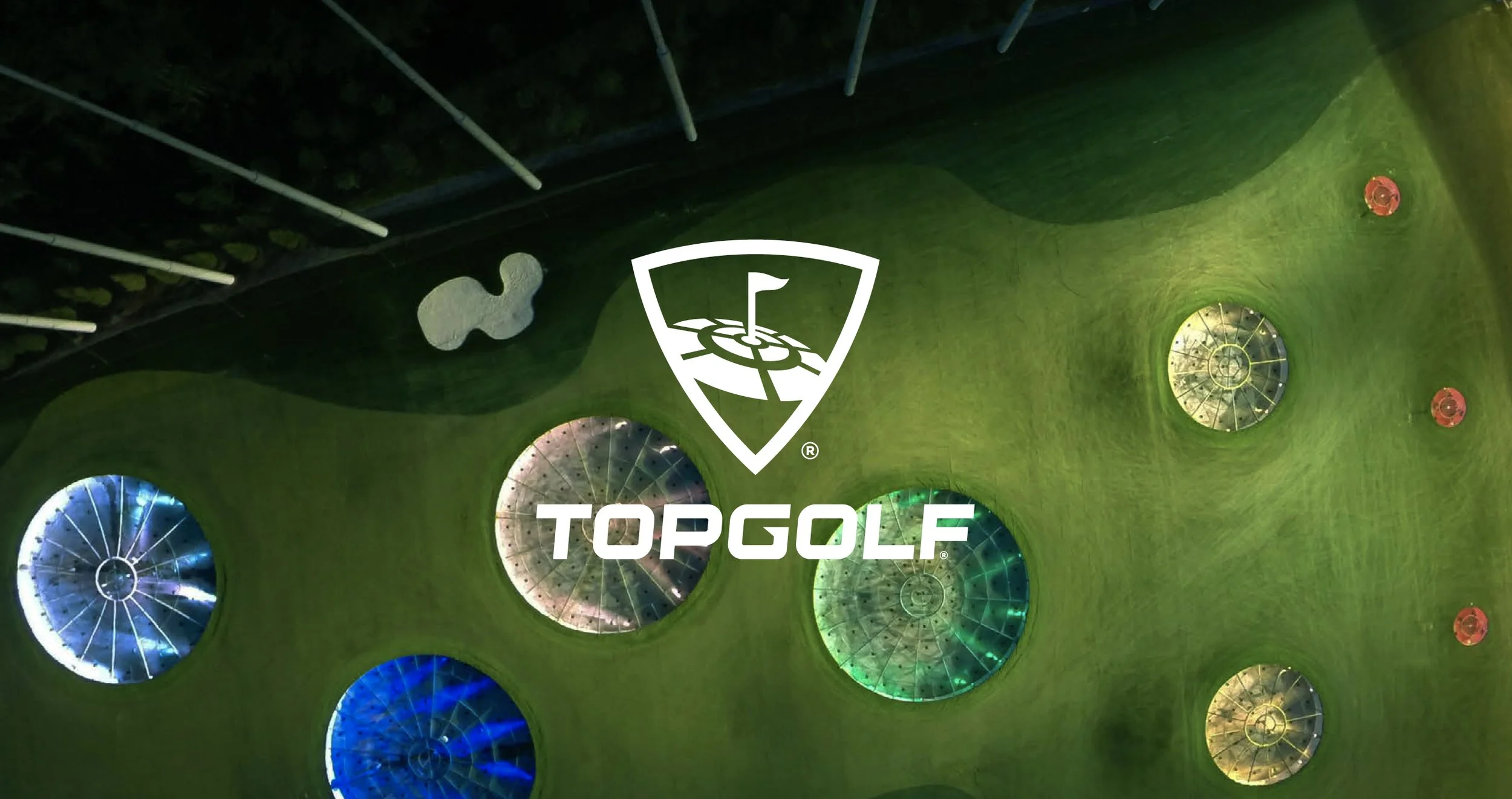 Aerial view of a golf course with several water hazards and lights, branded with the Topgolf logo.