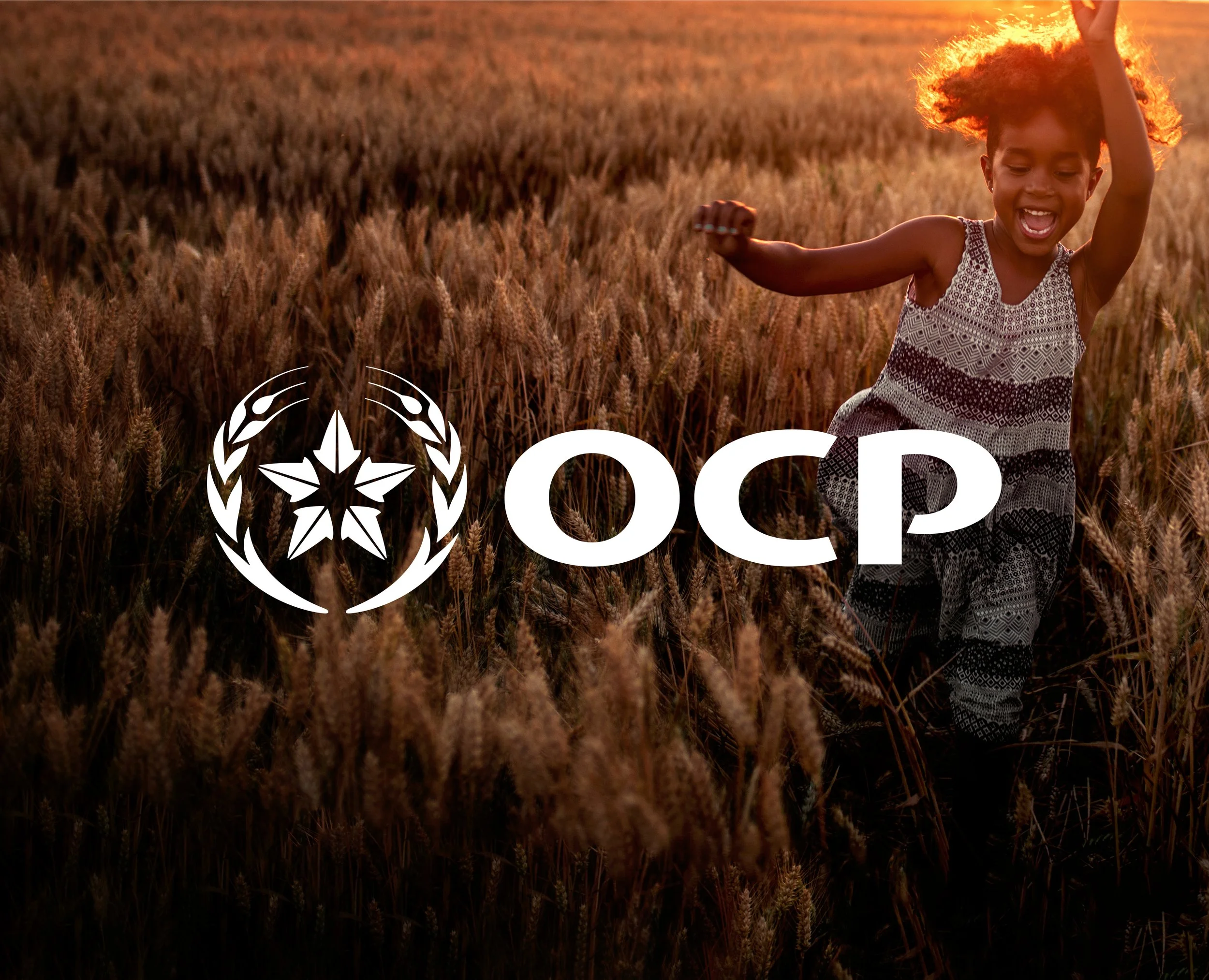 A child running or playing through a wheat field at sunset with the OCP logo overlayed