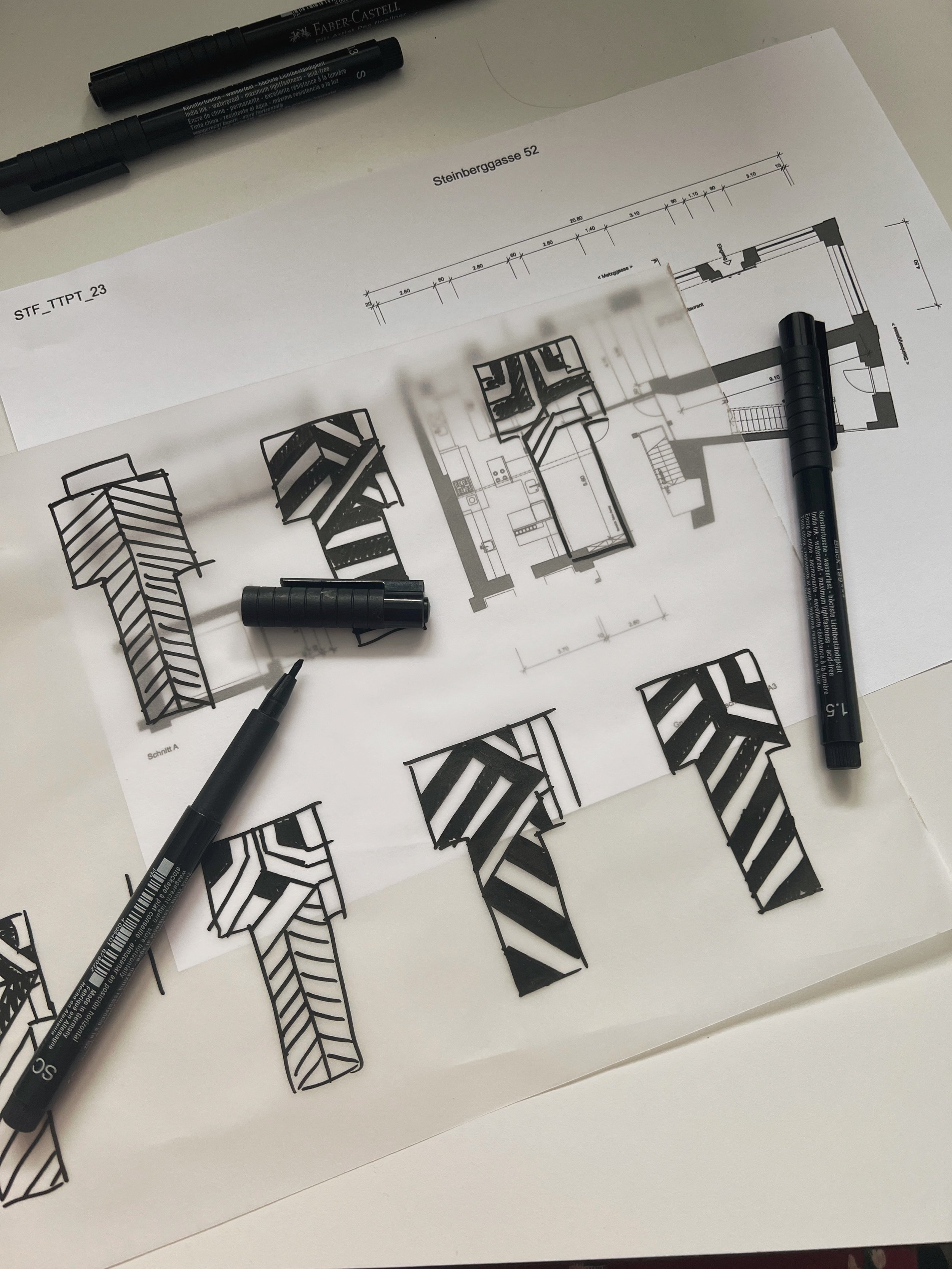 Baupläne und Skizzen für ein architektonisches Projekt, mit Markern und Zeichnungen auf einem Tisch.