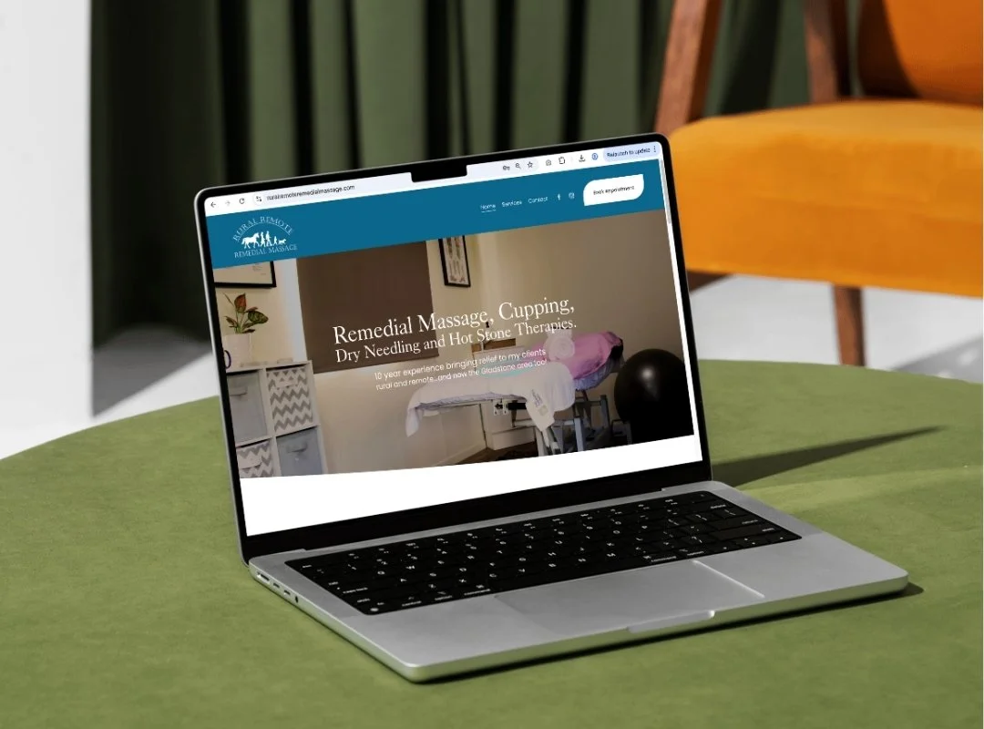 Open laptop with a website about remedial massage on a green table in a room with chairs.