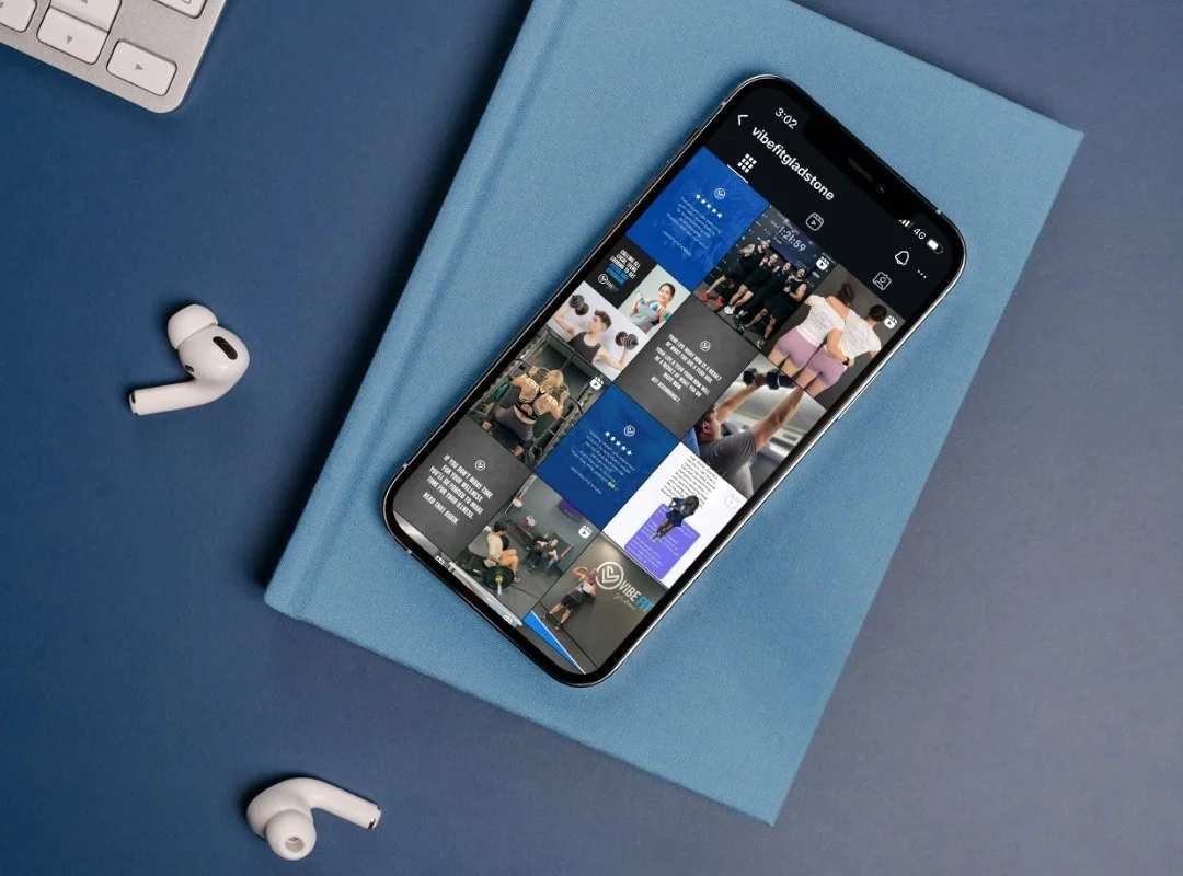 Smartphone with social media feed on blue cloth, wireless earphones and keyboard on blue background.