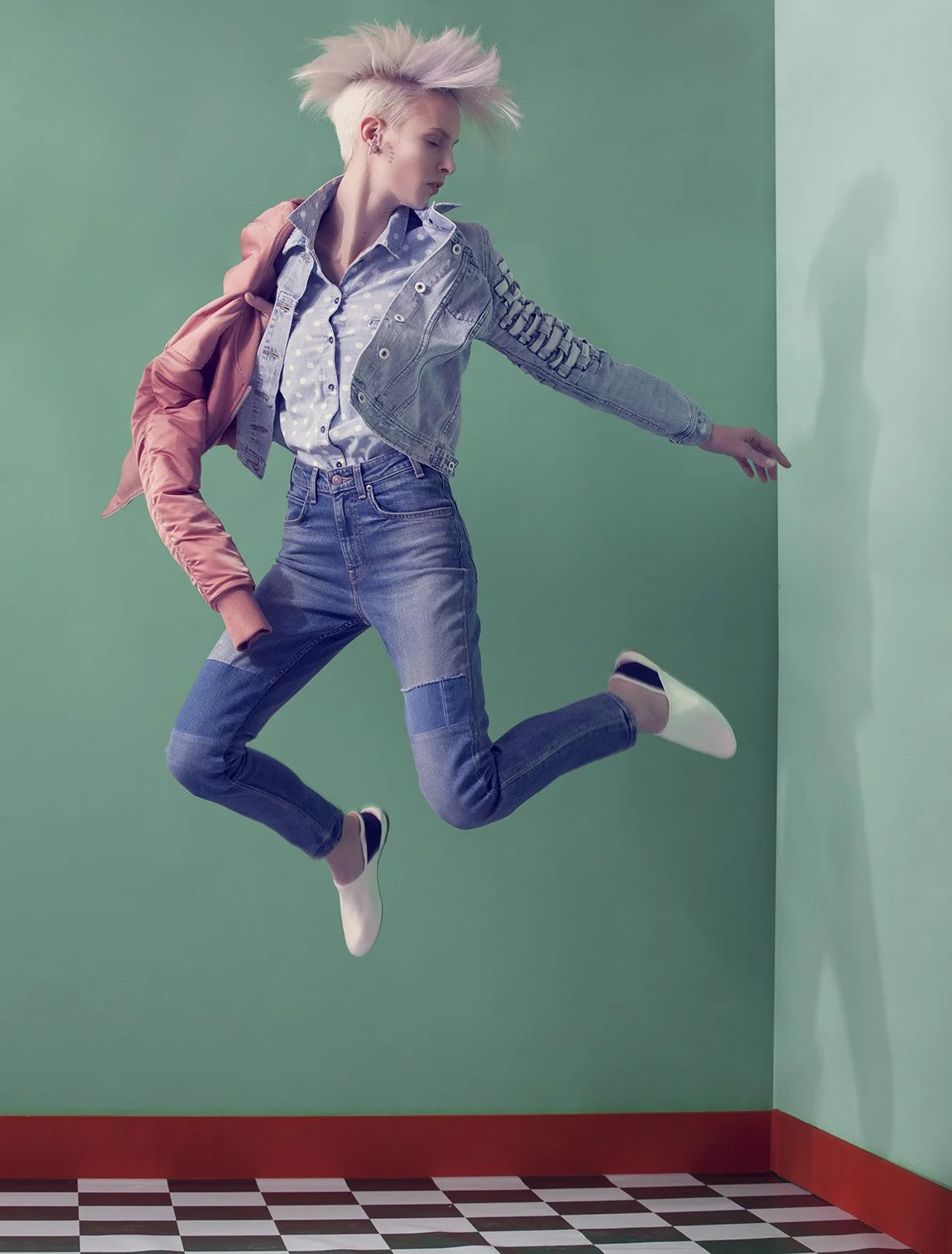 Editorial fashion image featuring model captured mid-air leap in denim ensemble within graphic corner set, set design and prop styling by Steffi Bühlmaier, photography by Christina Sandrock for Jolie, 2016
