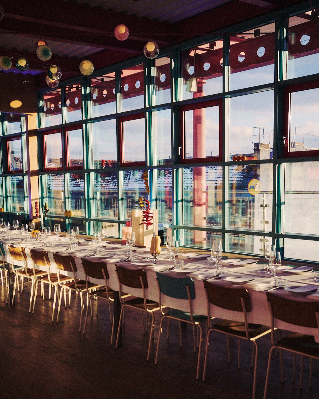 Long dinner table installation with sculptural produce centerpieces in sunset light, event design and props styling by Steffi Bühlmaier for Lidl x Highsnobiety dinner at Ember Rooftop Berlin, production by PS:KAAS, 2025