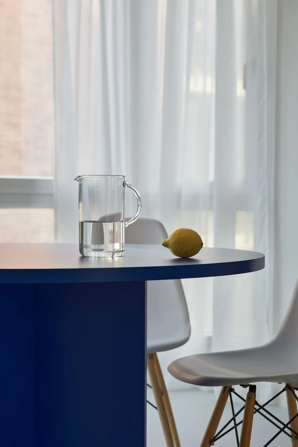 Dining table detail with blue round table, glass carafe and lemon, apartment in Berlin Mitte, interior design and styling by Steffi Bühlmaier, photography by Tobias Bärmann, 2024