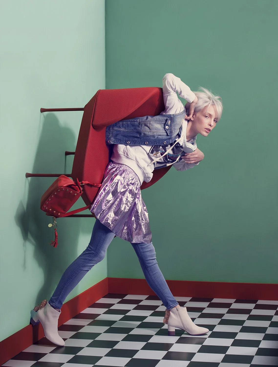 Editorial fashion image featuring model walking with chair worn as sculptural accessory across geometric set, set design and prop styling by Steffi Bühlmaier, photography by Christina Sandrock for Jolie, 2016