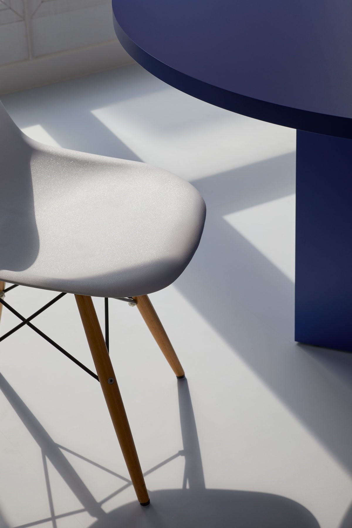 Modern dining chair and blue table detail with natural light and shadows, apartment in Berlin Mitte, interior design and styling by Steffi Bühlmaier, photography by Tobias Bärmann, 2024