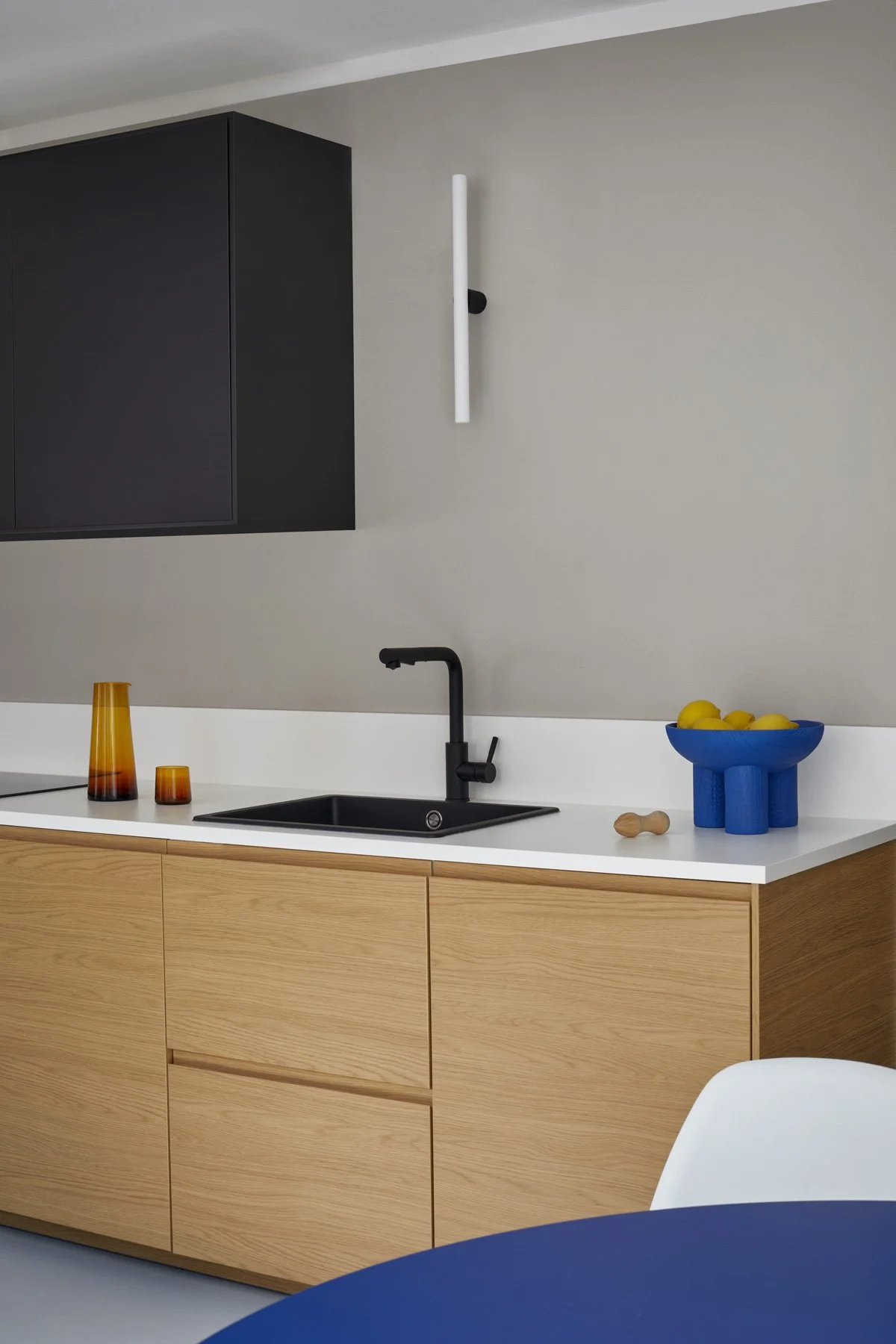 Minimal kitchen with oak cabinets, black sink and blue fruit bowl with lemons, apartment in Berlin Mitte, interior design, Innenausbau, Ausstattung and styling by Steffi Bühlmaier, photography by Tobias Bärmann, 2024