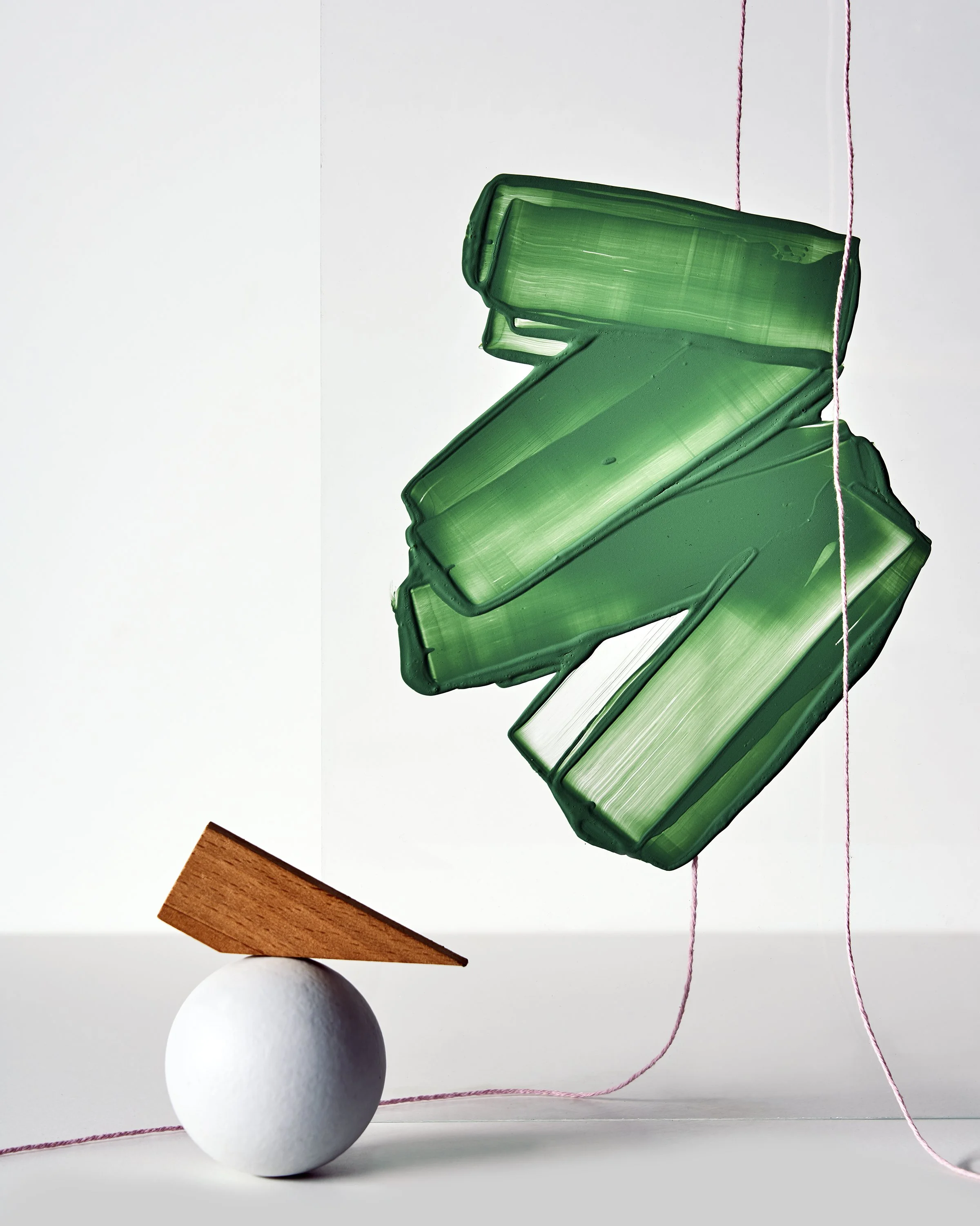 Still life composition with green paint on glass form and white sphere, art direction and props styling by Steffi Bühlmaier, photography by tobias bärmann