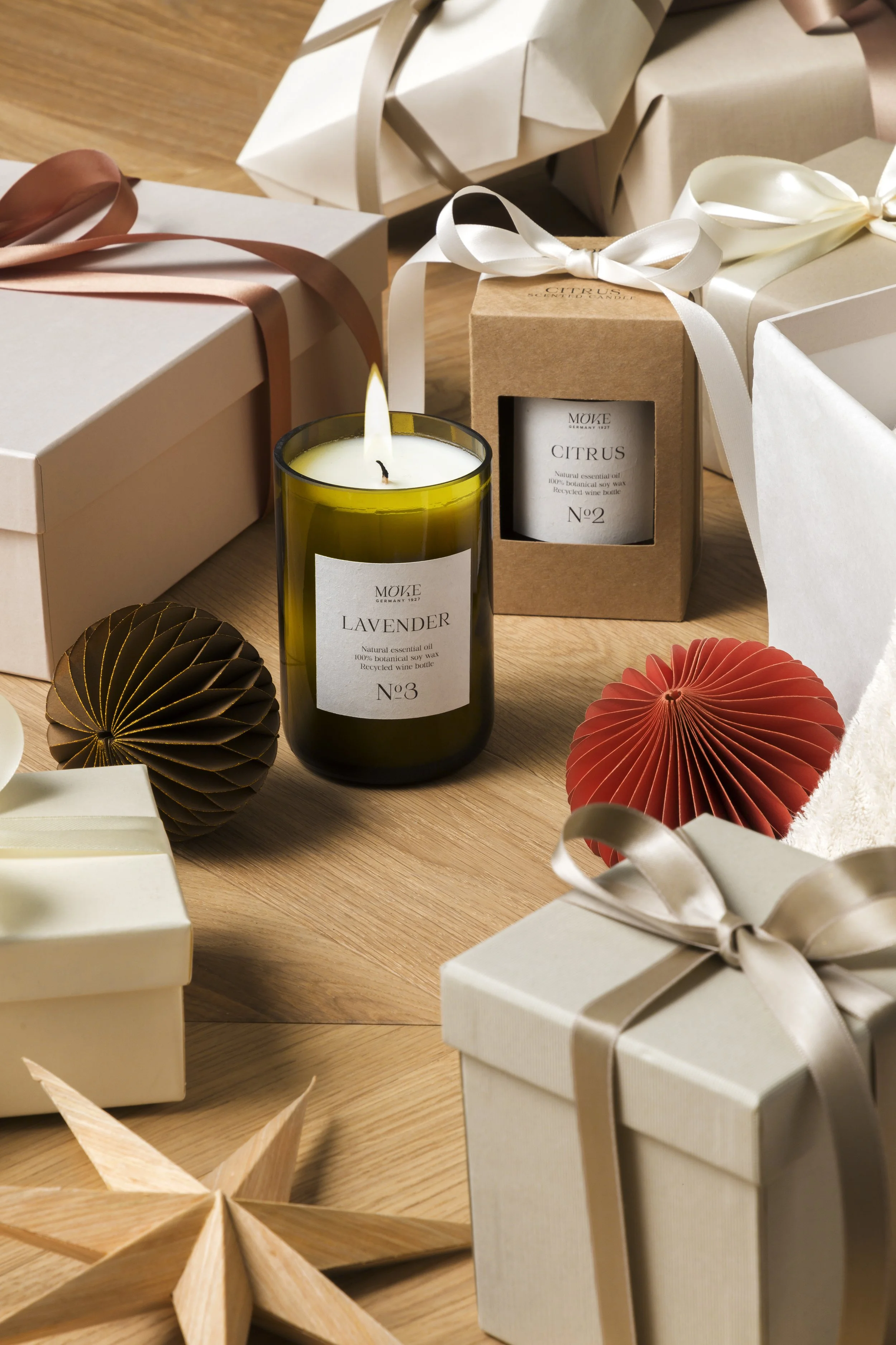 Still life of the öve christmas campaign featuring scented candles and gift packaging arranged among wrapped presents and paper ornaments, set construction and props styling by Steffi Bühlmaier, photography by Michael Tewes, creative direction by Stu