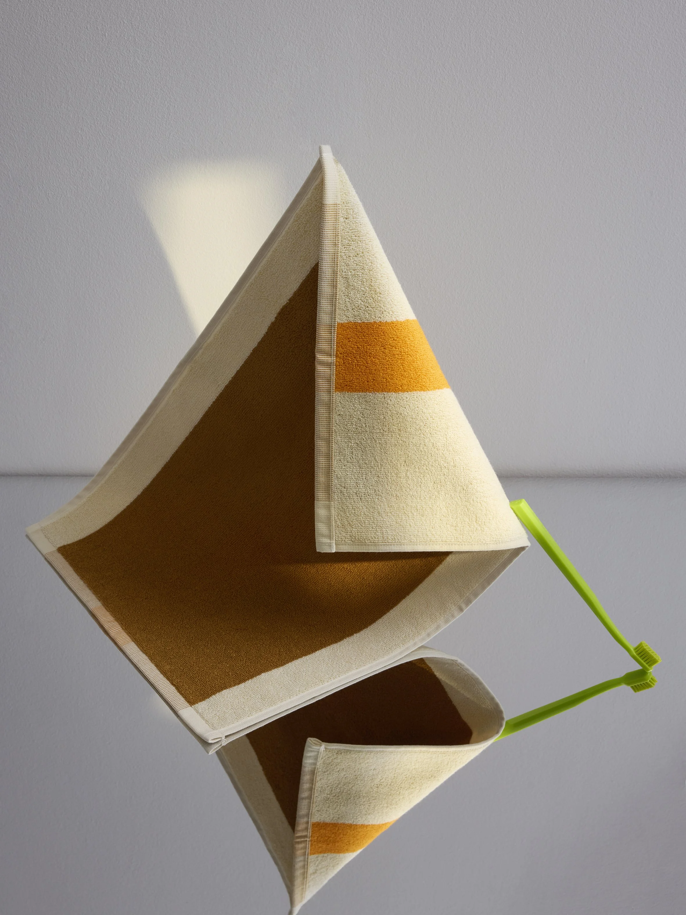 Sculptural still life with folded towel and toothbrush in geometric composition, art direction and styling by Steffi Bühlmaier, photography by anne deppe