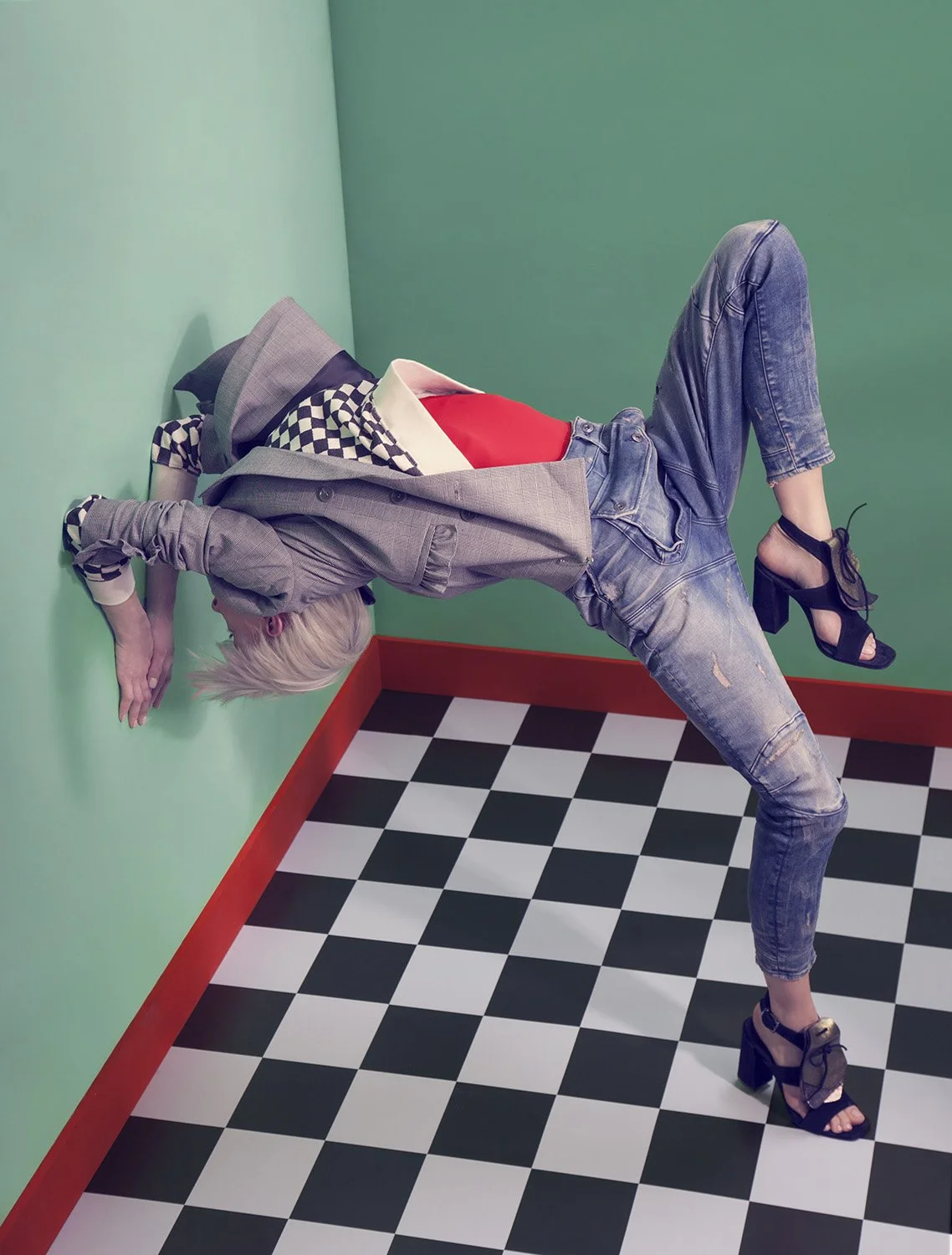 Editorial fashion image featuring model arched backward between walls in layered tailoring and denim, set design and prop styling by Steffi Bühlmaier, photography by Christina Sandrock for Jolie, 2016